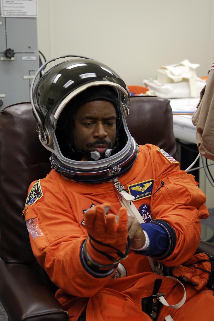 KENNEDY SPACE CENTER, FLA. --  Space shuttle Atlantis STS-122 Mission Specialist Leland Melvin tries on the gloves of his launch and entry suit, preparing for launch. The fitting is part of terminal countdown demonstration test, or TCDT, activities the crew is undertaking at NASA's Kennedy Space Center.  The TCDT provides astronauts and ground crews with equipment familiarization, emergency egress training and a simulated launch countdown. On mission STS-122, Atlantis will deliver the Columbus module to the International Space Station. The European Space Agency's largest single contribution to the station, Columbus is a multifunctional, pressurized laboratory that will be permanently attached to U.S. Node 2, called Harmony. The laboratory will expand the research facilities aboard the station, providing crew members and scientists from around the world the ability to conduct a variety of experiments in the physical, materials and life sciences. Launch is targeted for Dec. 6.  Photo credit: NASA/Kim Shiflett