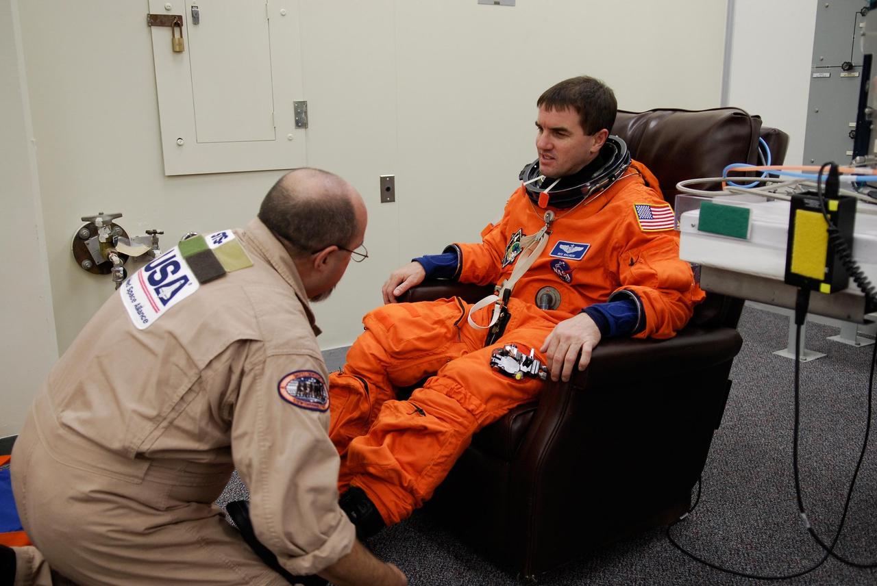 KENNEDY SPACE CENTER, FLA. --  A suit technician helps Space shuttle Atlantis STS-122 Mission Specialist Rex Walheim put on his launch and entry suit, preparing for launch. The fitting is part of terminal countdown demonstration test, or TCDT, activities the crew is undertaking at NASA's Kennedy Space Center.  The TCDT provides astronauts and ground crews with equipment familiarization, emergency egress training and a simulated launch countdown. On mission STS-122, Atlantis will deliver the Columbus module to the International Space Station. The European Space Agency's largest single contribution to the station, Columbus is a multifunctional, pressurized laboratory that will be permanently attached to U.S. Node 2, called Harmony. The laboratory will expand the research facilities aboard the station, providing crew members and scientists from around the world the ability to conduct a variety of experiments in the physical, materials and life sciences. Launch is targeted for Dec. 6.  Photo credit: NASA/Kim Shiflett