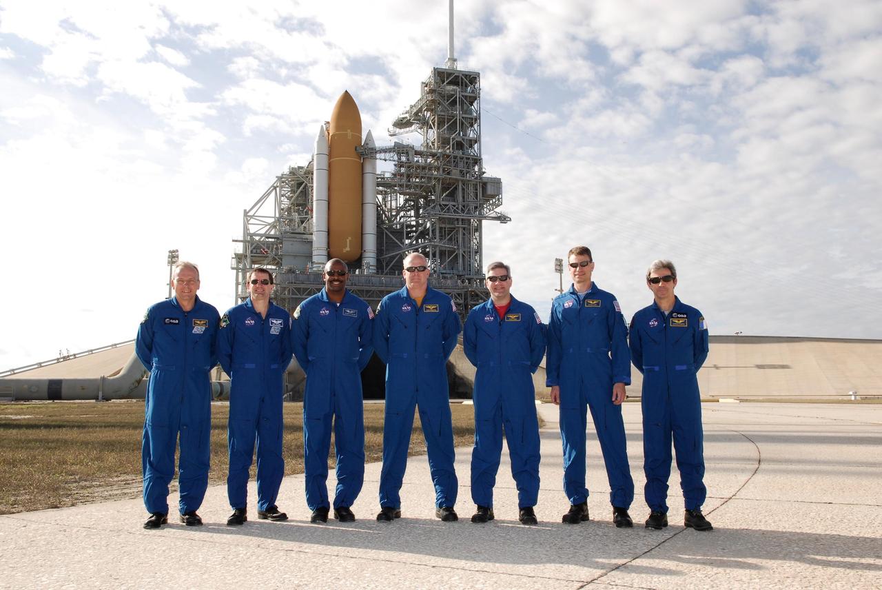 KENNEDY SPACE CENTER, FLA. --  The space shuttle Atlantis STS-122 crew poses for a group portrait at Launch Pad 39A as Atlantis undergoes final preparations for launch behind them.  From left are Mission Specialists Hans Schlegel, Rex Walheim and Leland Melvin; Pilot Alan Poindexter; Commander Steve Frick; and Mission Specialists Stanley Love and Leopold Eyharts.  Schlegel and Eyharts are with the European Space Agency.  Eyharts will remain on the International Space Station as a flight engineer for Expedition 16 following the STS-122 mission.  The STS-122 crew is at NASA's Kennedy Space Center to take part in terminal countdown demonstration test, or TCDT, activities, a standard part of launch preparations. The TCDT provides astronauts and ground crews with equipment familiarization, emergency egress training and a simulated launch countdown. On mission STS-122, Atlantis will deliver the European Space Agency's Columbus module to the International Space Station.  Columbus is a multifunctional, pressurized laboratory that will be permanently attached to U.S. Node 2, called Harmony, and will expand the research facilities aboard the station. Launch is targeted for Dec. 6.  Photo credit: NASA/Kim Shiflett