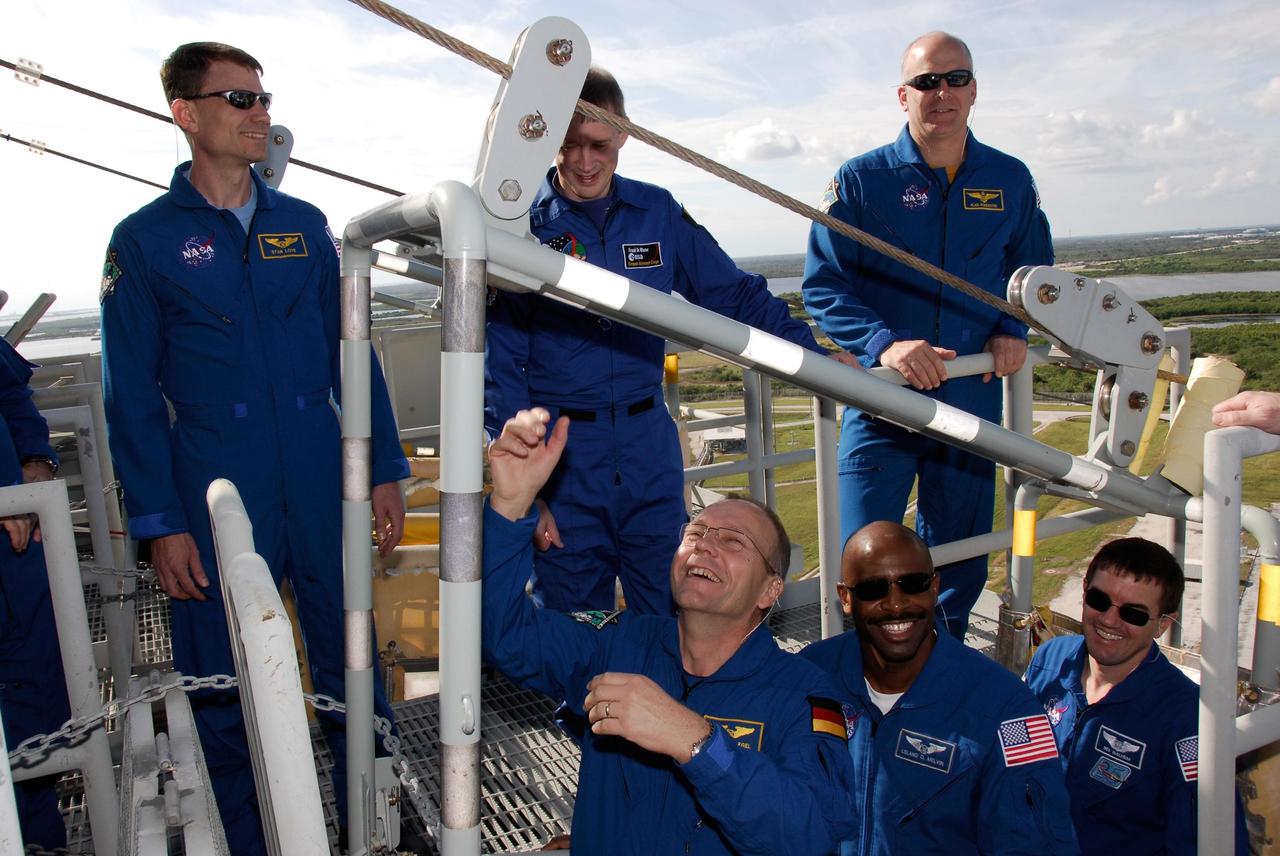 KENNEDY SPACE CENTER, FLA. -- The space shuttle Atlantis STS-122 crew receives instruction on slidewire basket operation, part of the emergency exit system on the fixed service structure on Launch Pad 39A. Standing, from left, are Mission Specialists Stanley Love; Leopold Eyharts' backup, Frank De Winne; and Pilot Alan Poindexter. Standing in the basket, from left, are Mission Specialists Hans Schlegel, Leland Melvin and Rex Walheim. Schlegel, Eyharts and De Winne are with the European Space Agency. Eyharts will remain on the International Space Station as a flight engineer for Expedition 16 following the STS-122 mission. Seven slidewire baskets are available to carry the crew from the level of the pad's Orbiter Access Arm to a safe landing site below, if needed. Each basket can hold up to three people. A braking system catch net and drag chain slow, and then halt, the baskets as they travel down the wire at approximately 55 miles per hour. The journey takes about half a minute. A bunker is located in the landing zone 1,200 feet west of the pad, with an M-113 armored personnel carrier stationed nearby. The STS-122 crew is at NASA's Kennedy Space Center to take part in terminal countdown demonstration test, or TCDT, activities, a standard part of launch preparations. The TCDT provides astronauts and ground crews with equipment familiarization and a simulated launch countdown before launch. On mission STS-122, Atlantis will deliver the European Space Agency's Columbus module to the International Space Station. Columbus is a multifunctional, pressurized laboratory that will be permanently attached to U.S. Node 2, called Harmony, and will expand the research facilities aboard the station. Launch is targeted for Dec. 6. Photo credit: NASA/Kim Shiflett