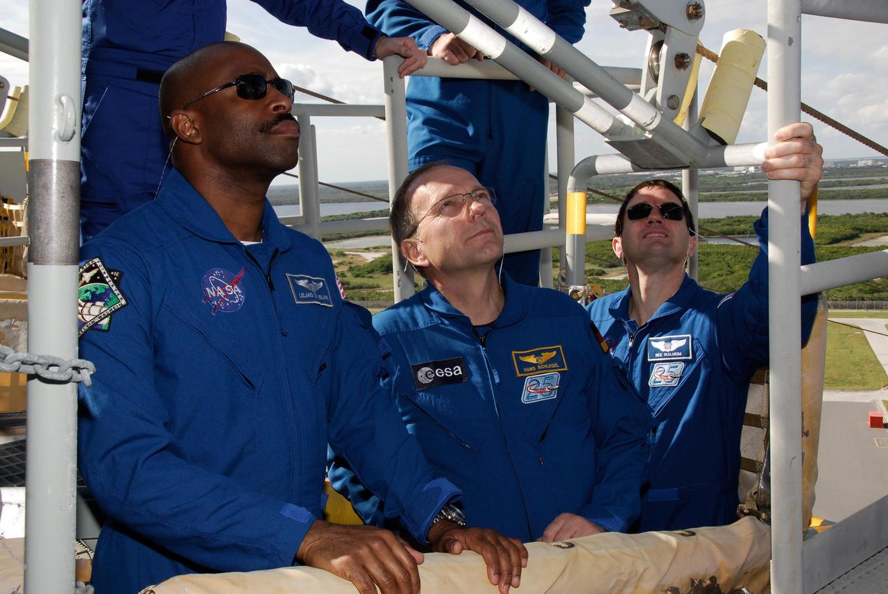 KENNEDY SPACE CENTER, FLA. -- The space shuttle Atlantis STS-122 crew receives instruction on slidewire basket operation, part of the emergency exit system on the fixed service structure on Launch Pad 39A. Standing in the basket, from left, are Mission Specialists Leland Melvin, Hans Schlegel and Rex Walheim. Schlegel is with the European Space Agency. Seven slidewire baskets are available to carry the crew from the level of the pad's Orbiter Access Arm to a safe landing site below, if needed. Each basket can hold up to three people. A braking system catch net and drag chain slow, and then halt, the baskets as they travel down the wire at approximately 55 miles per hour. The journey takes about half a minute. A bunker is located in the landing zone 1,200 feet west of the pad, with an M-113 armored personnel carrier stationed nearby. The STS-122 crew is at NASA's Kennedy Space Center to take part in terminal countdown demonstration test, or TCDT, activities, a standard part of launch preparations. The TCDT provides astronauts and ground crews with equipment familiarization and a simulated launch countdown before launch. On mission STS-122, Atlantis will deliver the European Space Agency's Columbus module to the International Space Station. Columbus is a multifunctional, pressurized laboratory that will be permanently attached to U.S. Node 2, called Harmony, and will expand the research facilities aboard the station. Launch is targeted for Dec. 6. Photo credit: NASA/Kim Shiflett