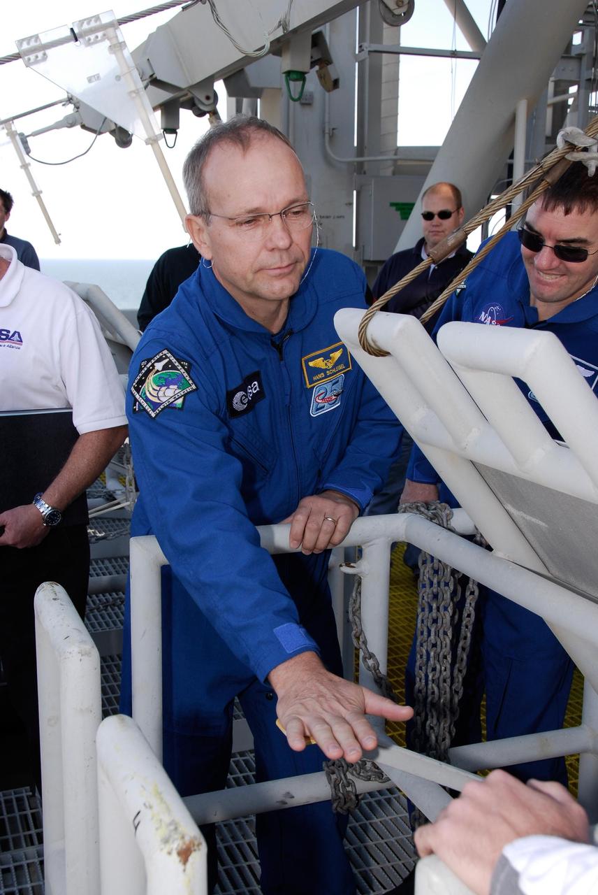 KENNEDY SPACE CENTER, FLA. -- During a training session, space shuttle Atlantis STS-122 Mission Specialist Hans Schlegel releases a slidewire basket, part of the emergency exit system on the fixed service structure on Launch Pad 39A, as Mission Specialist Rex Walheim looks on. Schlegel is with the European Space Agency. Seven slidewire baskets are available to carry the crew from the level of the pad's Orbiter Access Arm to a safe landing site below, if needed. Each basket can hold up to three people. A braking system catch net and drag chain slow, and then halt, the baskets as they travel down the wire at approximately 55 miles per hour. The journey takes about half a minute. A bunker is located in the landing zone 1,200 feet west of the pad, with an M-113 armored personnel carrier stationed nearby. The STS-122 crew is at NASA's Kennedy Space Center to take part in terminal countdown demonstration test, or TCDT, activities, a standard part of launch preparations. The TCDT provides astronauts and ground crews with equipment familiarization and a simulated launch countdown before launch. On mission STS-122, Atlantis will deliver the European Space Agency's Columbus module to the International Space Station. Columbus is a multifunctional, pressurized laboratory that will be permanently attached to U.S. Node 2, called Harmony, and will expand the research facilities aboard the station. Launch is targeted for Dec. 6. Photo credit: NASA/Kim Shiflett