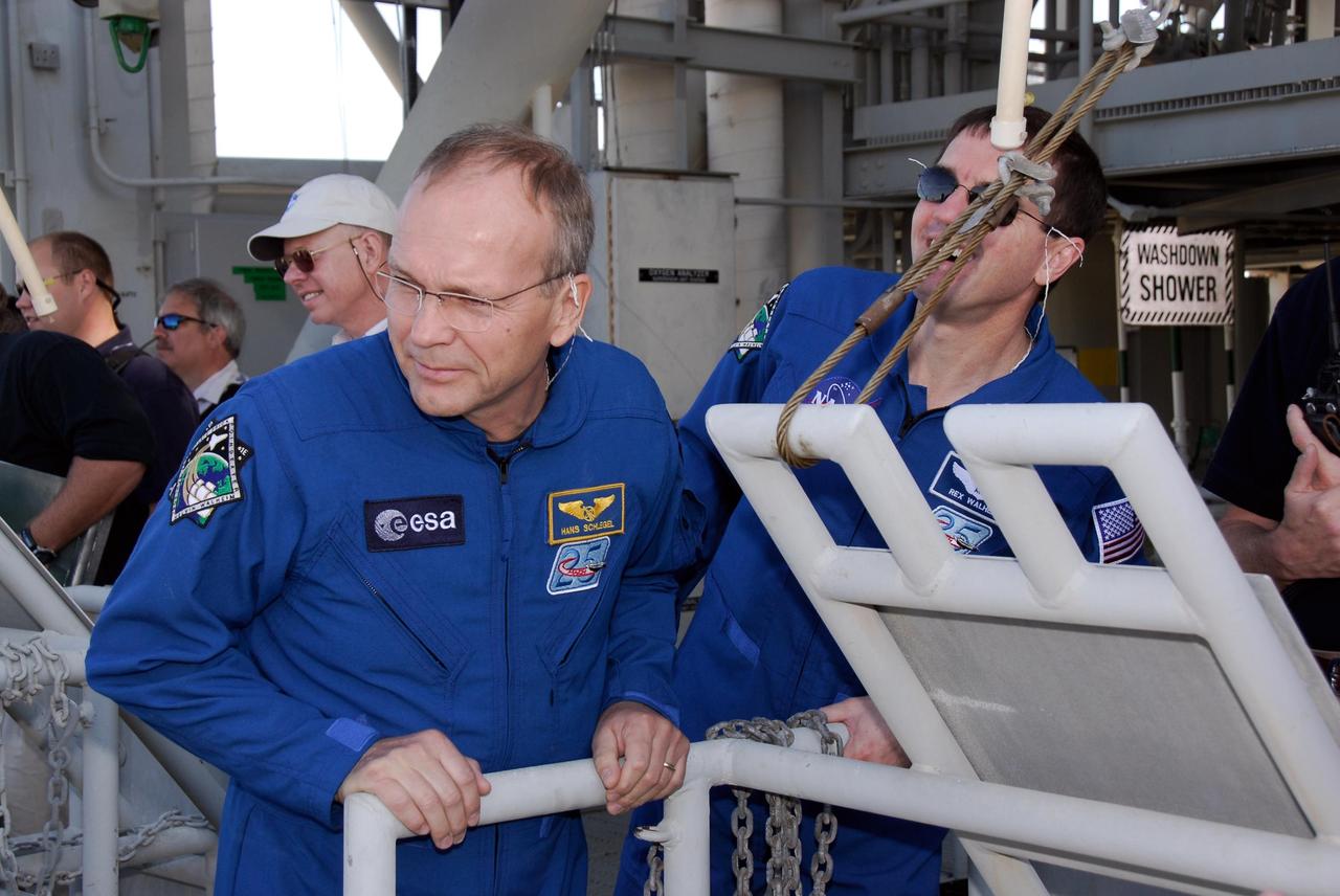 KENNEDY SPACE CENTER, FLA. -- During a training session on emergency exit from the fixed service structure on Launch Pad 39A, space shuttle Atlantis STS-122 Mission Specialists Hans Schlegel, left, and Rex Walheim watch a slidewire basket descend to the landing zone. Schlegel is with the European Space Agency. Seven slidewire baskets are available to carry the crew from the level of the pad's Orbiter Access Arm to a safe landing site below, if needed. Each basket can hold up to three people. A braking system catch net and drag chain slow, and then halt, the baskets as they travel down the wire at approximately 55 miles per hour. The journey takes about half a minute. A bunker is located in the landing zone 1,200 feet west of the pad, with an M-113 armored personnel carrier stationed nearby. The STS-122 crew is at NASA's Kennedy Space Center to take part in terminal countdown demonstration test, or TCDT, activities, a standard part of launch preparations. The TCDT provides astronauts and ground crews with equipment familiarization and a simulated launch countdown before launch. On mission STS-122, Atlantis will deliver the European Space Agency's Columbus module to the International Space Station. Columbus is a multifunctional, pressurized laboratory that will be permanently attached to U.S. Node 2, called Harmony, and will expand the research facilities aboard the station. Launch is targeted for Dec. 6. Photo credit: NASA/Kim Shiflett