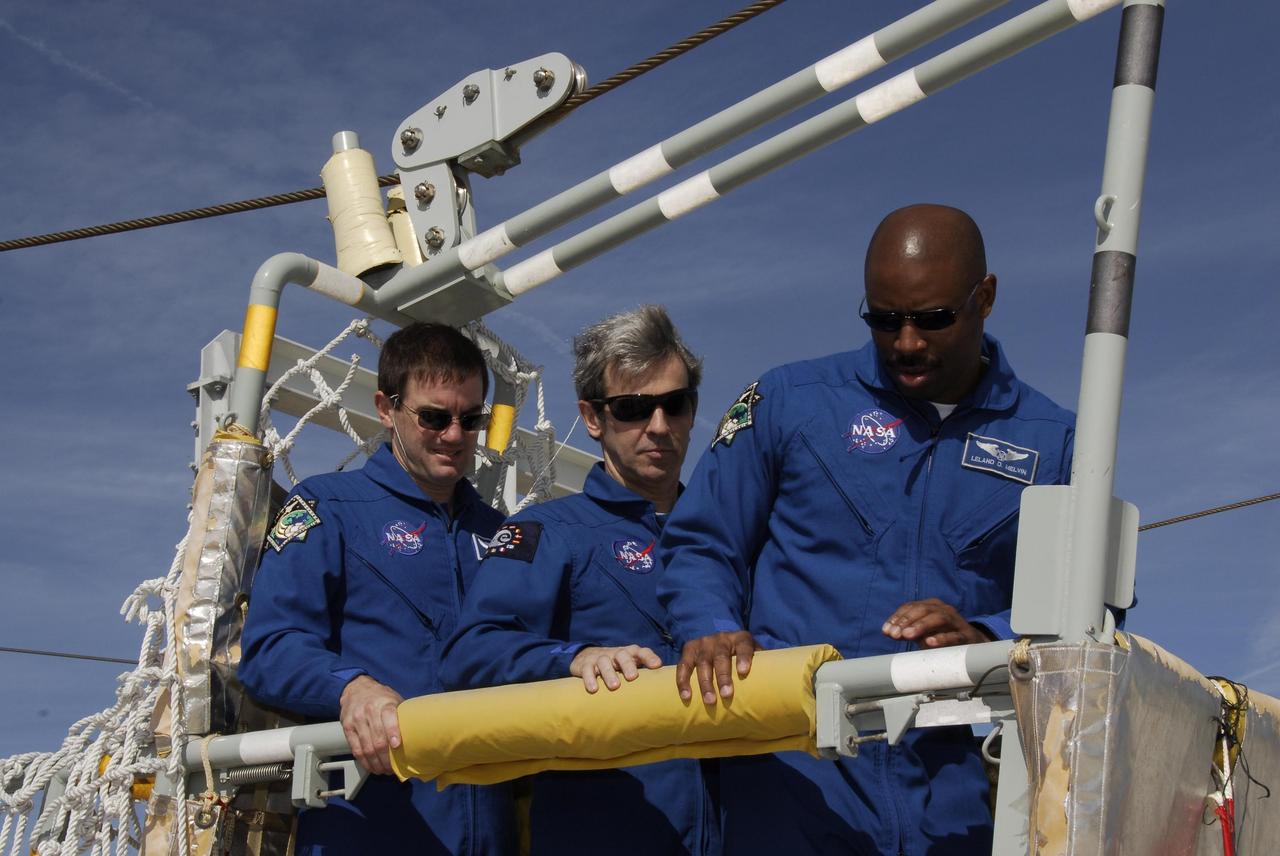 KENNEDY SPACE CENTER, FLA. -- The space shuttle Atlantis STS-122 crew receives instruction on slidewire basket operation, part of the emergency exit system on the fixed service structure on Launch Pad 39A. From left, Mission Specialists Rex Walheim, Leopold Eyharts and Leland Melvin gain first-hand experience inside one of the baskets. Seven slidewire baskets are available to carry the crew from the level of the pad's Orbiter Access Arm to this landing site, if needed. Each basket can hold up to three people. A braking system catch net and drag chain slow, and then halt, the baskets as they travel down the wire at approximately 55 miles per hour. The journey takes about half a minute. A bunker is located in the landing zone 1,200 feet west of the pad, with an M-113 armored personnel carrier stationed nearby. The STS-122 crew is at NASA's Kennedy Space Center to take part in terminal countdown demonstration test, or TCDT, activities, a standard part of launch preparations. The TCDT provides astronauts and ground crews with equipment familiarization and a simulated launch countdown before launch. On mission STS-122, Atlantis will deliver the European Space Agency's Columbus module to the International Space Station. Columbus is a multifunctional, pressurized laboratory that will be permanently attached to U.S. Node 2, called Harmony, and will expand the research facilities aboard the station. Launch is targeted for Dec. 6. Photo credit: NASA/Kim Shiflett