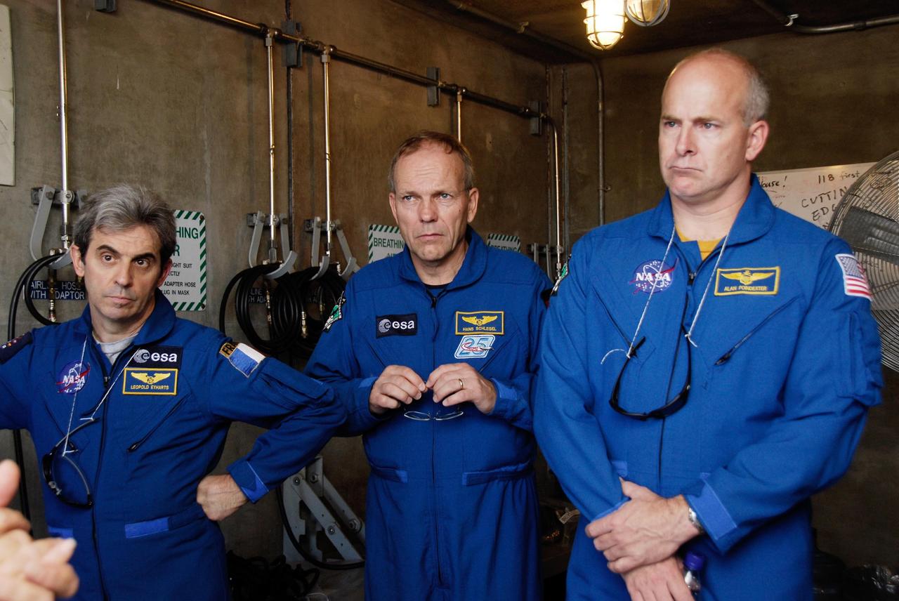 KENNEDY SPACE CENTER, FLA. -- The space shuttle Atlantis STS-122 crew receives instruction on the emergency exit system on Launch Pad 39A. Inside the bunker at the foot of the pad, Mission Specialists Leopold Eyharts and Hans Schlegel, both with the European Space Agency, and Pilot Alan Poindexter give their full attention to their trainer. Seven slidewire baskets are available to carry the crew from the level of the pad's Orbiter Access Arm to a safe landing site below, if needed. Each basket can hold up to three people. A braking system catch net and drag chain slow, and then halt, the baskets as they travel down the wire at approximately 55 miles per hour. The journey takes about half a minute. A bunker is located in the landing zone 1,200 feet west of the pad, with an M-113 armored personnel carrier stationed nearby. The STS-122 crew is at NASA's Kennedy Space Center to take part in terminal countdown demonstration test, or TCDT, activities, a standard part of launch preparations. The TCDT provides astronauts and ground crews with equipment familiarization and a simulated launch countdown before launch. On mission STS-122, Atlantis will deliver the European Space Agency's Columbus module to the International Space Station. Columbus is a multifunctional, pressurized laboratory that will be permanently attached to U.S. Node 2, called Harmony, and will expand the research facilities aboard the station. Launch is targeted for Dec. 6. Photo credit: NASA/Kim Shiflett