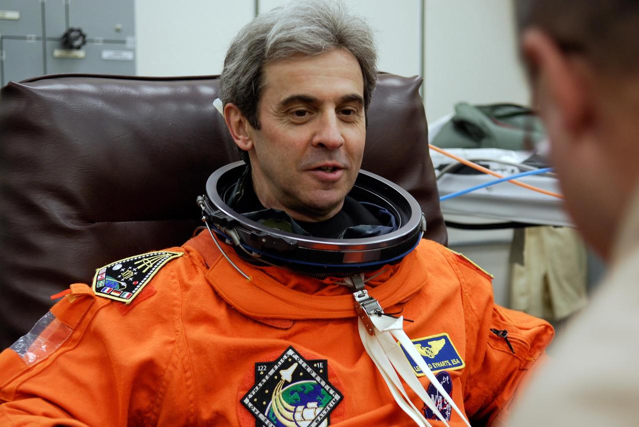 KENNEDY SPACE CENTER, FLA. -- Space shuttle Atlantis STS-122 Mission Specialist Leopold Eyharts talks to the suit technician helping him put on his launch and entry suit, in astronaut crew quarters. A European Space Agency astronaut, Eyharts will remain on the International Space Station as a flight engineer for Expedition 16 following the STS-122 mission. The STS-122 crew is preparing for a simulated launch countdown aboard Atlantis, part of terminal countdown demonstration test, or TCDT, activities at NASA's Kennedy Space Center. The TCDT is a dress rehearsal for launch and also provides astronauts and ground crews with equipment familiarization and emergency egress training. On mission STS-122, Atlantis will deliver the Columbus module to the International Space Station. The European Space Agency's largest single contribution to the station, Columbus is a multifunctional, pressurized laboratory that will be permanently attached to U.S. Node 2, called Harmony. The laboratory will expand the research facilities aboard the station, providing crew members and scientists from around the world the ability to conduct a variety of experiments in the physical, materials and life sciences. Launch is targeted for Dec. 6. Photo credit: NASA/Kim Shiflett
