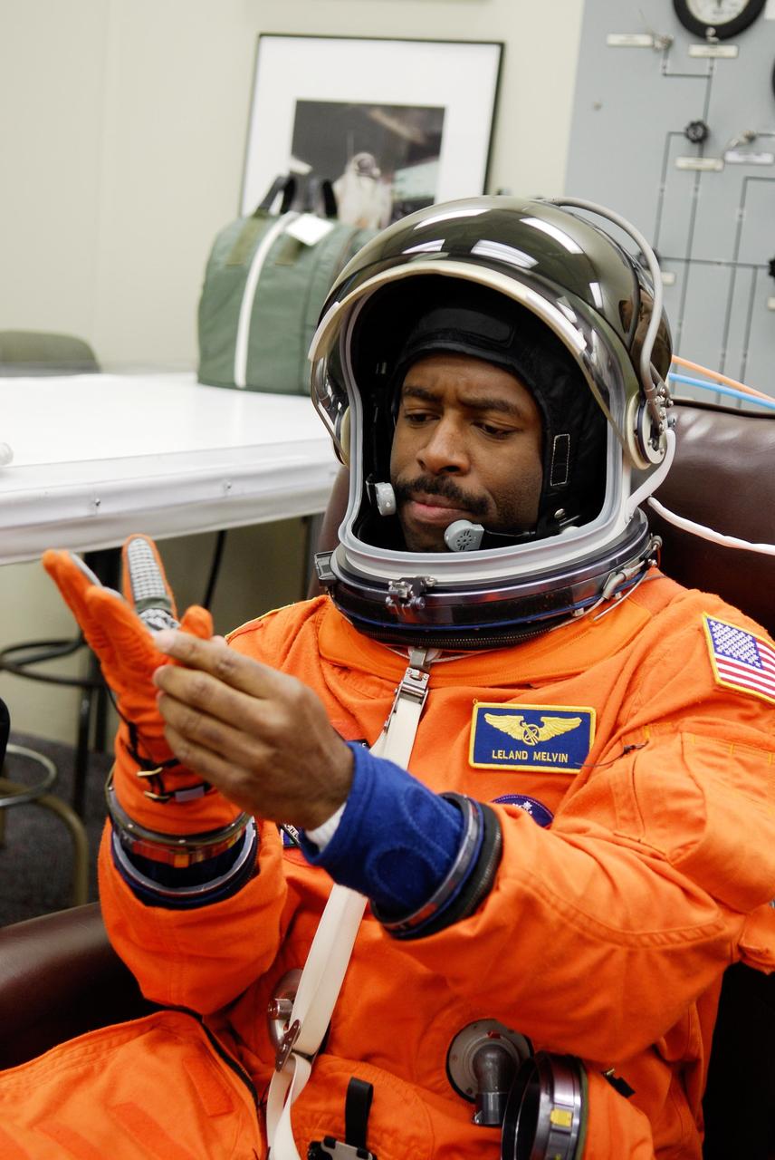 KENNEDY SPACE CENTER, FLA. -- Space shuttle Atlantis STS-122 Mission Specialist Leland Melvin puts on his gloves, part of his launch and entry suit, in astronaut crew quarters. The STS-122 crew is preparing for a simulated launch countdown aboard Atlantis, part of terminal countdown demonstration test, or TCDT, activities at NASA's Kennedy Space Center. The TCDT is a dress rehearsal for launch and also provides astronauts and ground crews with equipment familiarization and emergency egress training. On mission STS-122, Atlantis will deliver the Columbus module to the International Space Station. The European Space Agency's largest single contribution to the station, Columbus is a multifunctional, pressurized laboratory that will be permanently attached to U.S. Node 2, called Harmony. The laboratory will expand the research facilities aboard the station, providing crew members and scientists from around the world the ability to conduct a variety of experiments in the physical, materials and life sciences. Launch is targeted for Dec. 6. Photo credit: NASA/Kim Shiflett