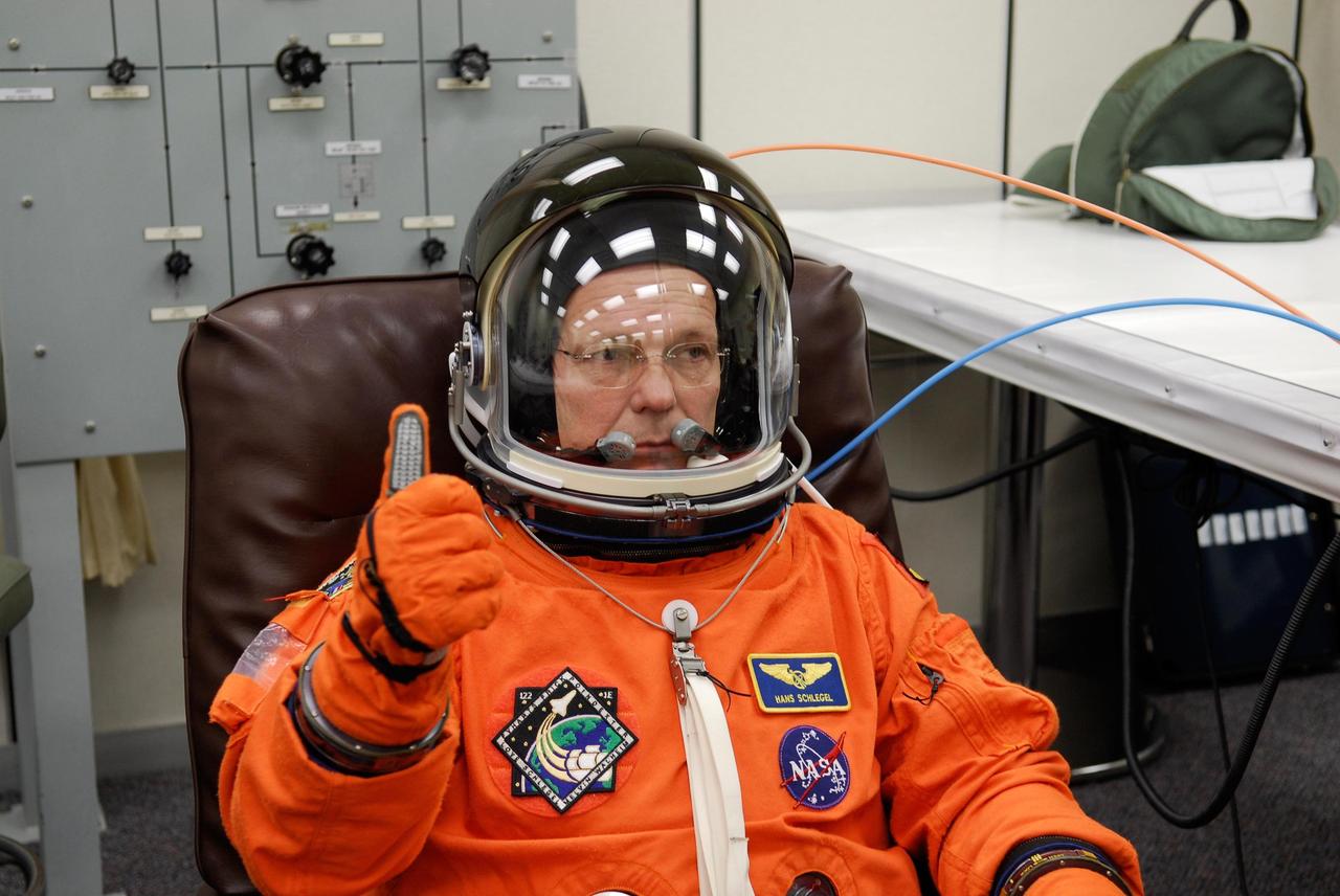 KENNEDY SPACE CENTER, FLA. -- In astronaut crew quarters, space shuttle Atlantis STS-122 Mission Specialist Hans Schlegel, with the European Space Agency, signals that his launch and entry suit is functioning properly. The STS-122 crew is preparing for a simulated launch countdown aboard Atlantis, part of terminal countdown demonstration test, or TCDT, activities at NASA's Kennedy Space Center. The TCDT is a dress rehearsal for launch and also provides astronauts and ground crews with equipment familiarization and emergency egress training. On mission STS-122, Atlantis will deliver the Columbus module to the International Space Station. The European Space Agency's largest single contribution to the station, Columbus is a multifunctional, pressurized laboratory that will be permanently attached to U.S. Node 2, called Harmony. The laboratory will expand the research facilities aboard the station, providing crew members and scientists from around the world the ability to conduct a variety of experiments in the physical, materials and life sciences. Launch is targeted for Dec. 6. Photo credit: NASA/Kim Shiflett