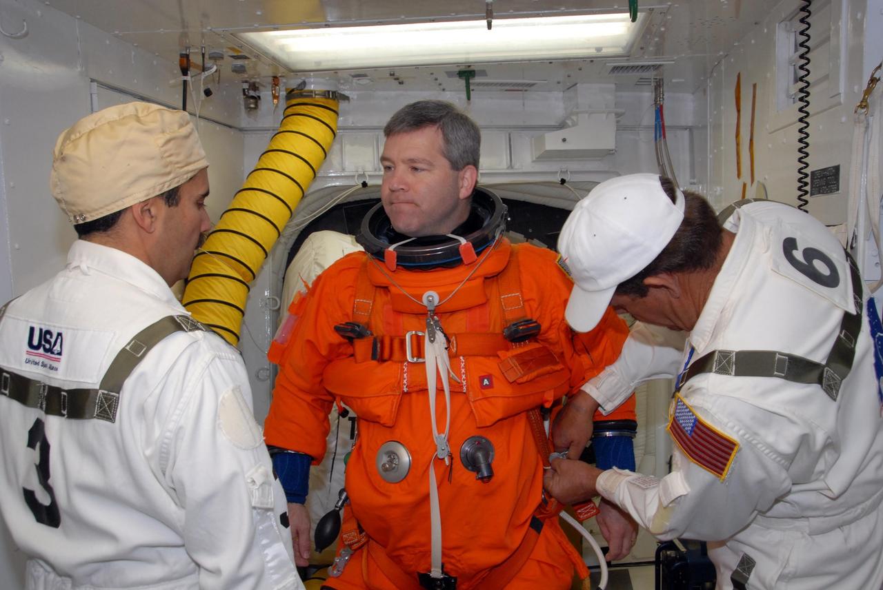 KENNEDY SPACE CENTER, FLA. --  In the White Room on Launch Pad 39A, suit technicians prepare space shuttle Atlantis STS-122 Commander Steve Frick for entry into Atlantis' cockpit, through the hatch behind him.   The exercise is part of terminal countdown demonstration test, or TCDT, activities at NASA's Kennedy Space Center. The TCDT is a dress rehearsal for launch and also provides astronauts and ground crews with equipment familiarization and emergency egress training.  On mission STS-122, Atlantis will deliver the Columbus module to the International Space Station. The European Space Agency's largest single contribution to the station, Columbus is a multifunctional, pressurized laboratory that will be permanently attached to U.S. Node 2, called Harmony. The laboratory will expand the research facilities aboard the station, providing crew members and scientists from around the world the ability to conduct a variety of experiments in the physical, materials and life sciences. Atlantis' launch is targeted for Dec. 6.  Photo credit: NASA/George Shelton