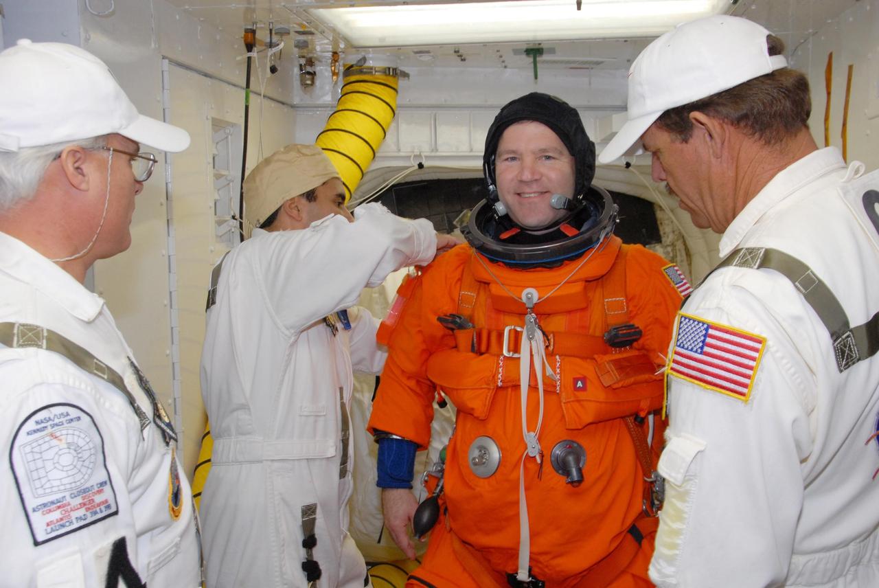 KENNEDY SPACE CENTER, FLA. --  In the White Room on Launch Pad 39A, suit technicians put the finishing touches on the flight and entry suit of space shuttle Atlantis STS-122 Commander Steve Frick for his entry into Atlantis' cockpit, through the hatch behind him.   The exercise is part of terminal countdown demonstration test, or TCDT, activities at NASA's Kennedy Space Center. The TCDT is a dress rehearsal for launch and also provides astronauts and ground crews with equipment familiarization and emergency egress training.  On mission STS-122, Atlantis will deliver the Columbus module to the International Space Station. The European Space Agency's largest single contribution to the station, Columbus is a multifunctional, pressurized laboratory that will be permanently attached to U.S. Node 2, called Harmony. The laboratory will expand the research facilities aboard the station, providing crew members and scientists from around the world the ability to conduct a variety of experiments in the physical, materials and life sciences. Atlantis' launch is targeted for Dec. 6.  Photo credit: NASA/George Shelton