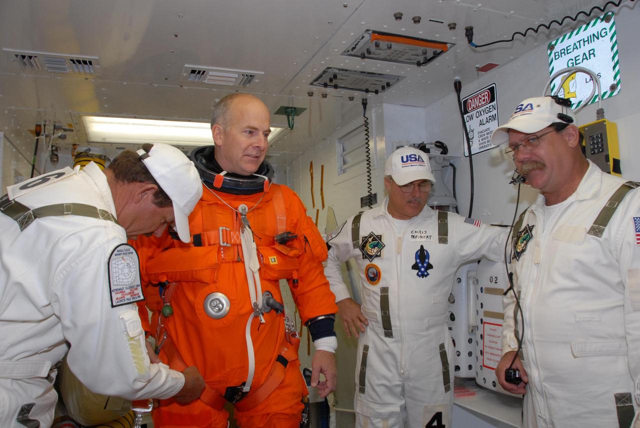 KENNEDY SPACE CENTER, FLA. --  In the White Room on Launch Pad 39A, suit technicians put the finishing touches on the flight and entry suit of space shuttle Atlantis STS-122 Pilot Alan Poindexter for his entry into Atlantis' cockpit.   The exercise is part of terminal countdown demonstration test, or TCDT, activities at NASA's Kennedy Space Center. The TCDT is a dress rehearsal for launch and also provides astronauts and ground crews with equipment familiarization and emergency egress training.  On mission STS-122, Atlantis will deliver the Columbus module to the International Space Station. The European Space Agency's largest single contribution to the station, Columbus is a multifunctional, pressurized laboratory that will be permanently attached to U.S. Node 2, called Harmony. The laboratory will expand the research facilities aboard the station, providing crew members and scientists from around the world the ability to conduct a variety of experiments in the physical, materials and life sciences. Atlantis' launch is targeted for Dec. 6.  Photo credit: NASA/George Shelton