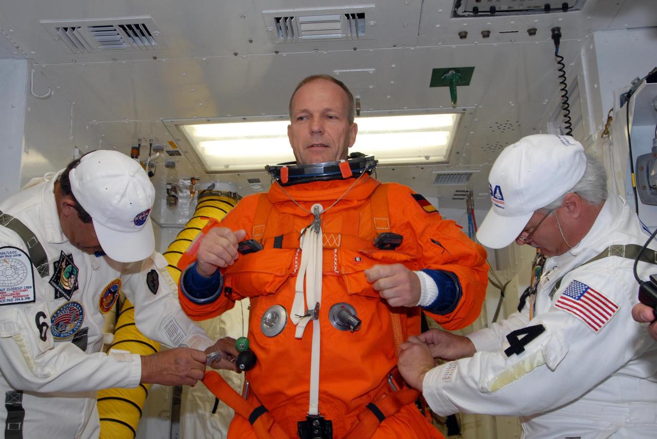 KENNEDY SPACE CENTER, FLA. --  In the White Room on Launch Pad 39A, suit technicians help space shuttle Atlantis STS-122 Mission Specialist Hans Schlegel with his flight and entry suit before his entry onto Atlantis' flight deck.  Schlegel is with the European Space Agency.   The exercise is part of terminal countdown demonstration test, or TCDT, activities at NASA's Kennedy Space Center. The TCDT is a dress rehearsal for launch and also provides astronauts and ground crews with equipment familiarization and emergency egress training.  On mission STS-122, Atlantis will deliver the Columbus module to the International Space Station. The European Space Agency's largest single contribution to the station, Columbus is a multifunctional, pressurized laboratory that will be permanently attached to U.S. Node 2, called Harmony. The laboratory will expand the research facilities aboard the station, providing crew members and scientists from around the world the ability to conduct a variety of experiments in the physical, materials and life sciences. Atlantis' launch is targeted for Dec. 6.  Photo credit: NASA/George Shelton