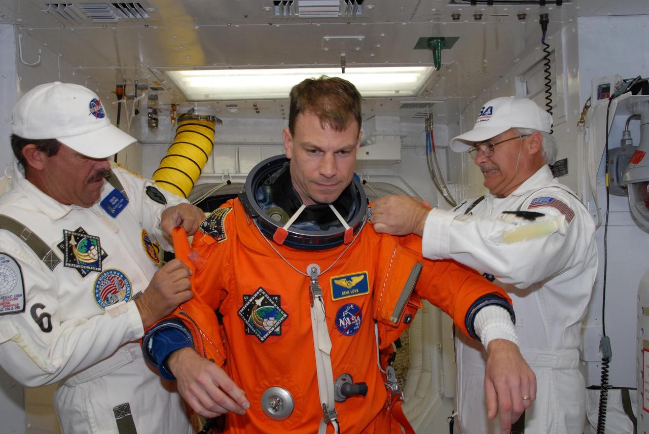 KENNEDY SPACE CENTER, FLA. --  In the White Room on Launch Pad 39A, suit technicians help space shuttle Atlantis STS-122 Mission Specialist Stanley Love with his flight and entry suit before his entry onto Atlantis' flight deck, through the hatch behind him.    The exercise is part of terminal countdown demonstration test, or TCDT, activities at NASA's Kennedy Space Center. The TCDT is a dress rehearsal for launch and also provides astronauts and ground crews with equipment familiarization and emergency egress training.  On mission STS-122, Atlantis will deliver the Columbus module to the International Space Station. The European Space Agency's largest single contribution to the station, Columbus is a multifunctional, pressurized laboratory that will be permanently attached to U.S. Node 2, called Harmony. The laboratory will expand the research facilities aboard the station, providing crew members and scientists from around the world the ability to conduct a variety of experiments in the physical, materials and life sciences. Atlantis' launch is targeted for Dec. 6.  Photo credit: NASA/George Shelton