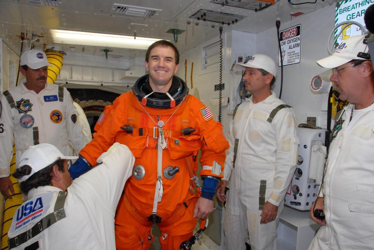 KENNEDY SPACE CENTER, FLA. --  In the White Room on Launch Pad 39A, suit technicians help space shuttle Atlantis STS-122 Mission Specialist Rex Walheim with his flight and entry suit before his entry onto Atlantis' flight deck, through the hatch behind him.   The exercise is part of terminal countdown demonstration test, or TCDT, activities at NASA's Kennedy Space Center. The TCDT is a dress rehearsal for launch and also provides astronauts and ground crews with equipment familiarization and emergency egress training.  On mission STS-122, Atlantis will deliver the Columbus module to the International Space Station. The European Space Agency's largest single contribution to the station, Columbus is a multifunctional, pressurized laboratory that will be permanently attached to U.S. Node 2, called Harmony. The laboratory will expand the research facilities aboard the station, providing crew members and scientists from around the world the ability to conduct a variety of experiments in the physical, materials and life sciences. Atlantis' launch is targeted for Dec. 6.  Photo credit: NASA/George Shelton