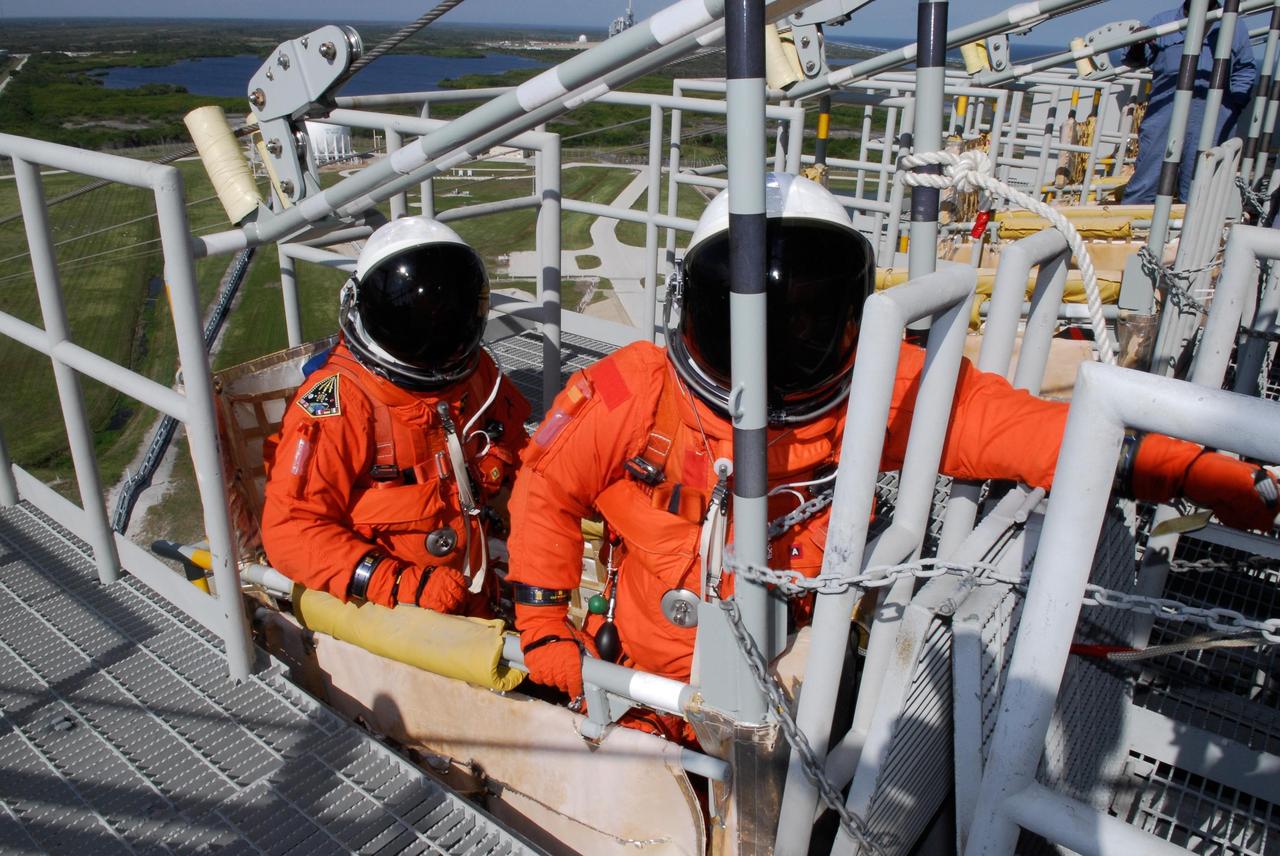 KENNEDY SPACE CENTER, FLA. --  Members of space shuttle Atlantis' STS-122 crew practice emergency exit procedures in a slidewire basket at Launch Pad 39A following a simulated launch countdown.   The exercise is part of terminal countdown demonstration test, or TCDT, activities at NASA's Kennedy Space Center. The TCDT is a dress rehearsal for launch and also provides astronauts and ground crews with equipment familiarization and emergency egress training.  On mission STS-122, Atlantis will deliver the Columbus module to the International Space Station. The European Space Agency's largest single contribution to the station, Columbus is a multifunctional, pressurized laboratory that will be permanently attached to U.S. Node 2, called Harmony. The laboratory will expand the research facilities aboard the station, providing crew members and scientists from around the world the ability to conduct a variety of experiments in the physical, materials and life sciences. Atlantis' launch is targeted for Dec. 6.  Photo credit: NASA/Kim Shiflett