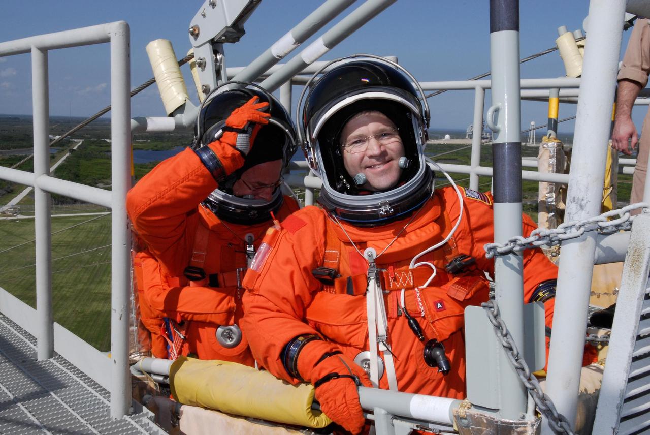 KENNEDY SPACE CENTER, FLA. --  Space shuttle Atlantis STS-122 Pilot Alan Poindexter, left, and Commander Steve Frick practice emergency exit procedures in a slidewire basket at Launch Pad 39A following a simulated launch countdown.   The exercise is part of terminal countdown demonstration test, or TCDT, activities at NASA's Kennedy Space Center. The TCDT is a dress rehearsal for launch and also provides astronauts and ground crews with equipment familiarization and emergency egress training.  On mission STS-122, Atlantis will deliver the Columbus module to the International Space Station. The European Space Agency's largest single contribution to the station, Columbus is a multifunctional, pressurized laboratory that will be permanently attached to U.S. Node 2, called Harmony. The laboratory will expand the research facilities aboard the station, providing crew members and scientists from around the world the ability to conduct a variety of experiments in the physical, materials and life sciences. Atlantis' launch is targeted for Dec. 6.  Photo credit: NASA/Kim Shiflett