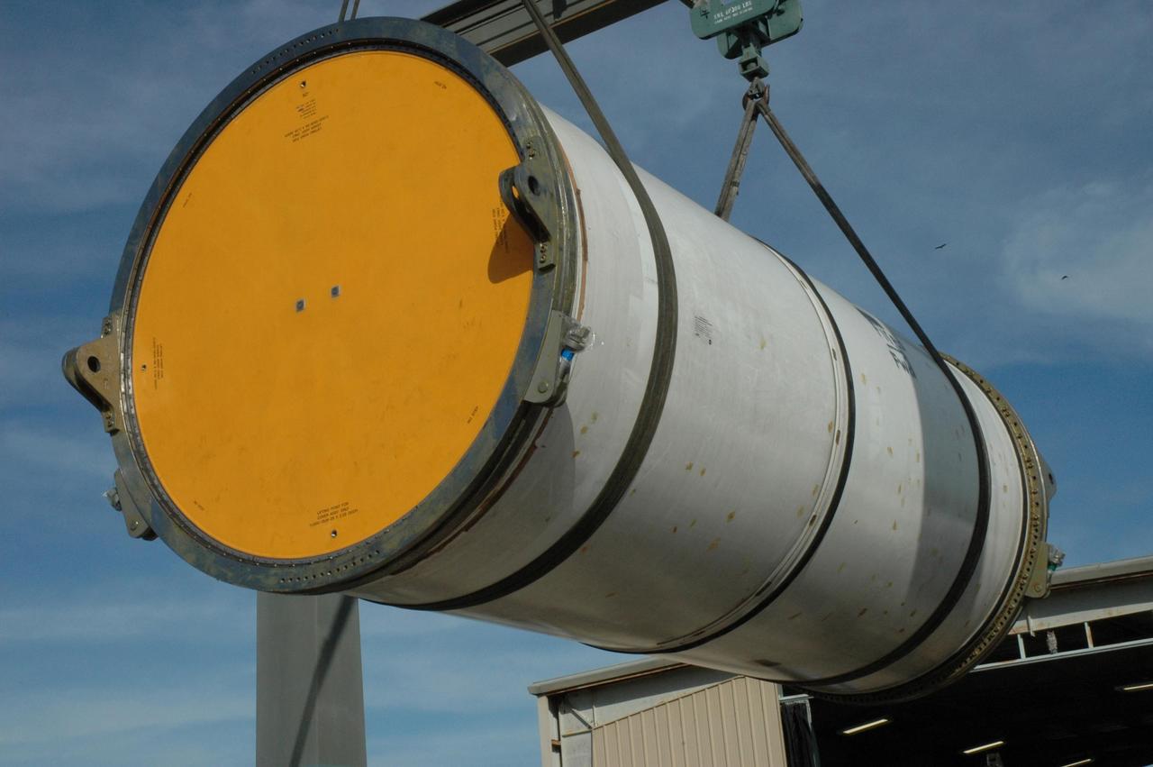 KENNEDY SPACE CENTER, FLA. --  An overhead crane lifts a solid rocket booster segment off a truck bed at the railroad yard at NASA's Kennedy Space Center for transfer to a railroad car.  The yellow transportation end cover has already been inserted and is secure.  The spent segment is part of the booster used to launch space shuttle Discovery in October. The segment will be covered for the long trip back to Utah.   After a mission, the spent boosters are recovered, cleaned, disassembled, refurbished and reused after each launch. After hydrolasing the interior of each segment, they are placed on flatbed trucks.  The individual booster segments are transferred to a railhead located at the railroad yard at NASA's Kennedy Space Center. The long train of segments is part of the twin solid rocket boosters used to launch space shuttle Discovery in October.  The NASA Railroad locomotive backs up the rail cars and the segment is lowered onto the car. The covered segments are moved to Titusville for interchange with Florida East Coast Railway to begin the trip back to Utah.  Photo credit: NASA/Amanda Diller