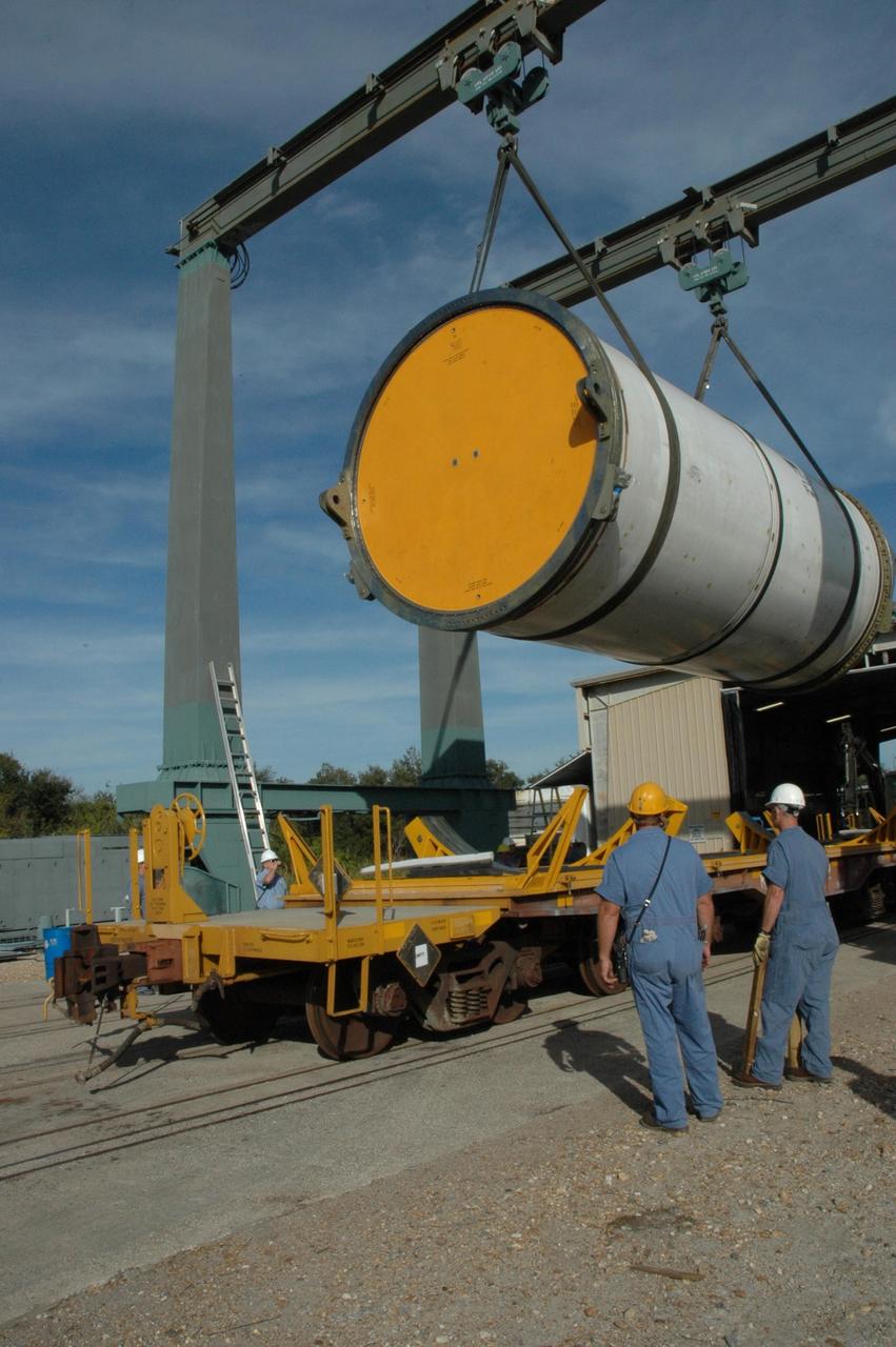 KENNEDY SPACE CENTER, FLA. --  An overhead crane lifts a solid rocket booster segment off a truck bed at the railroad yard at NASA's Kennedy Space Center for transfer to a railroad car.  The yellow transportation end cover has already been inserted and is secure.  The spent segment is part of the booster used to launch space shuttle Discovery in October. The segment will be placed on the car and covered for the long trip back to Utah.   After a mission, the spent boosters are recovered, cleaned, disassembled, refurbished and reused after each launch. After hydrolasing the interior of each segment, they are placed on flatbed trucks.  The individual booster segments are transferred to a railhead located at the railroad yard at NASA's Kennedy Space Center. The long train of segments is part of the twin solid rocket boosters used to launch space shuttle Discovery in October.  The NASA Railroad locomotive backs up the rail cars and the segment is lowered onto the car. The covered segments are moved to Titusville for interchange with Florida East Coast Railway to begin the trip back to Utah.  Photo credit: NASA/Amanda Diller
