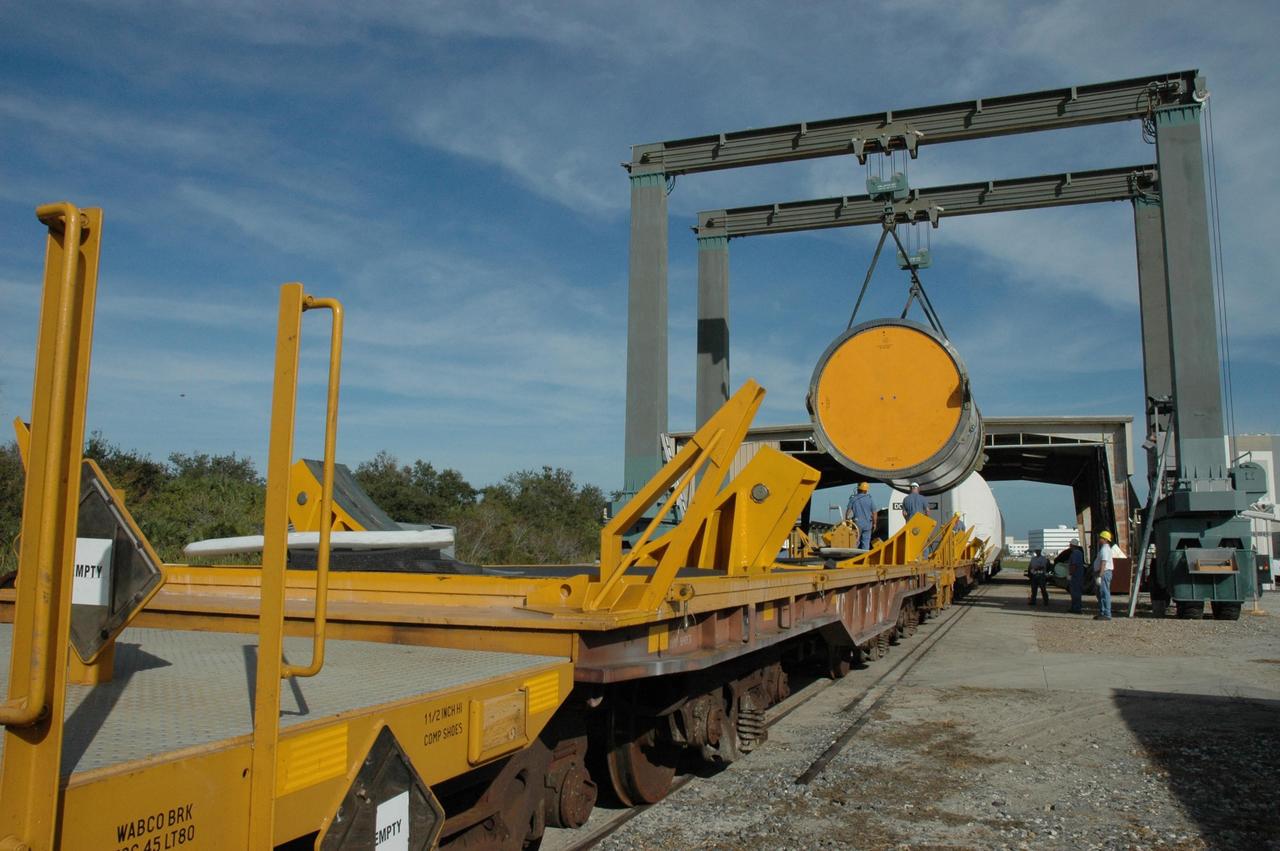 KENNEDY SPACE CENTER, FLA. --  An overhead crane moves a solid rocket booster segment toward a railroad car at the railroad yard at NASA's Kennedy Space Center.  The yellow transportation end cover has already been inserted and is secure.  The spent segment is part of the booster used to launch space shuttle Discovery in October. The segment will be placed on the car and covered for the long trip back to Utah.   After a mission, the spent boosters are recovered, cleaned, disassembled, refurbished and reused after each launch. After hydrolasing the interior of each segment, they are placed on flatbed trucks.  The individual booster segments are transferred to a railhead located at the railroad yard at NASA's Kennedy Space Center. The long train of segments is part of the twin solid rocket boosters used to launch space shuttle Discovery in October.  The NASA Railroad locomotive backs up the rail cars and the segment is lowered onto the car. The covered segments are moved to Titusville for interchange with Florida East Coast Railway to begin the trip back to Utah.  Photo credit: NASA/Amanda Diller