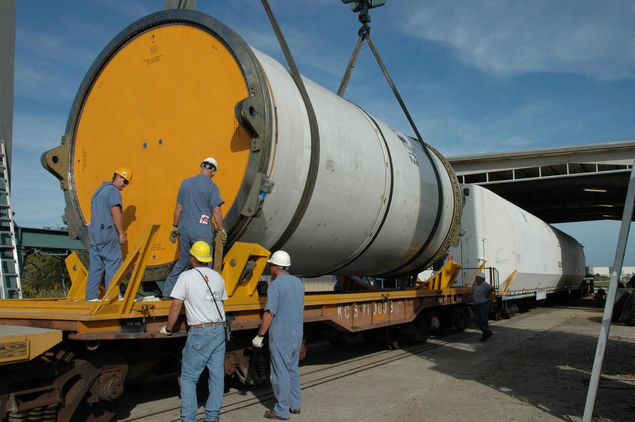 KENNEDY SPACE CENTER, FLA. --  Workers oversee the placement of a solid rocket booster segment onto a railroad car at the railroad yard at NASA's Kennedy Space Center.  The spent segment is part of the booster used to launch space shuttle Discovery in October.  At far right are other segments already covered for the long trip back to Utah.  After a mission, the spent boosters are recovered, cleaned, disassembled, refurbished and reused after each launch. After hydrolasing the interior of each segment, they are placed on flatbed trucks.  The individual booster segments are transferred to a railhead located at the railroad yard at NASA's Kennedy Space Center. The long train of segments is part of the twin solid rocket boosters used to launch space shuttle Discovery in October.  The NASA Railroad locomotive backs up the rail cars and the segment is lowered onto the car. The covered segments are moved to Titusville for interchange with Florida East Coast Railway to begin the trip back to Utah.  Photo credit: NASA/Amanda Diller