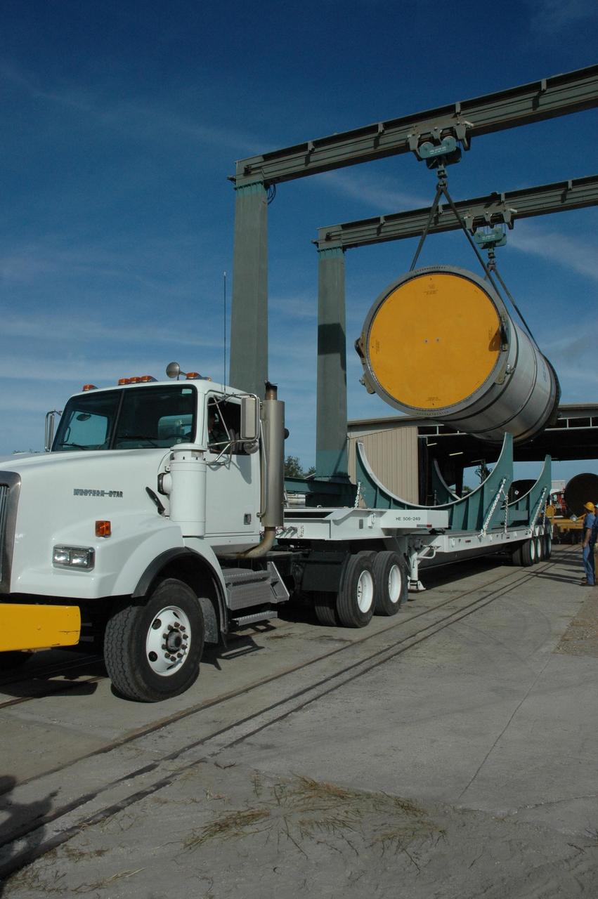 KENNEDY SPACE CENTER, FLA. --  A solid rocket booster segment is lifted off a truck bed at the railroad yard at NASA's Kennedy Space Center.  The yellow transportation end cover has already been inserted and is secure.  The segment is part of the booster used to launch space shuttle Discovery in October.  The spent segment will be placed on a railroad car and covered for the long trip back to Utah.   After a mission, the spent boosters are recovered, cleaned, disassembled, refurbished and reused after each launch. After hydrolasing the interior of each segment, they are placed on flatbed trucks.  The individual booster segments are transferred to a railhead located at the railroad yard at NASA's Kennedy Space Center. The long train of segments is part of the twin solid rocket boosters used to launch space shuttle Discovery in October.  The NASA Railroad locomotive backs up the rail cars and the segment is lowered onto the car. The covered segments are moved to Titusville for interchange with Florida East Coast Railway to begin the trip back to Utah.  Photo credit: NASA/Amanda Diller