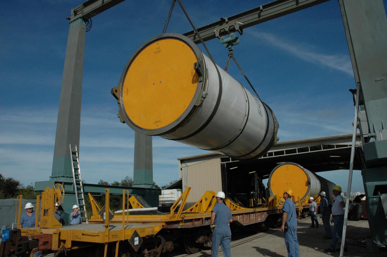 KENNEDY SPACE CENTER, FLA. --  An overhead crane lowers a solid rocket booster segment toward a railroad car at the railroad yard at NASA's Kennedy Space Center.  The yellow transportation end cover has already been inserted and is secure.  The spent segment is part of the booster used to launch space shuttle Discovery in October. The segment will be placed on the car and covered for the long trip back to Utah.   After a mission, the spent boosters are recovered, cleaned, disassembled, refurbished and reused after each launch. After hydrolasing the interior of each segment, they are placed on flatbed trucks.  The individual booster segments are transferred to a railhead located at the railroad yard at NASA's Kennedy Space Center. The long train of segments is part of the twin solid rocket boosters used to launch space shuttle Discovery in October.  The NASA Railroad locomotive backs up the rail cars and the segment is lowered onto the car. The covered segments are moved to Titusville for interchange with Florida East Coast Railway to begin the trip back to Utah.  Photo credit: NASA/Amanda Diller