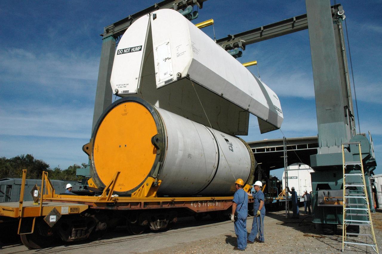 KENNEDY SPACE CENTER, FLA. --  At the railroad yard at NASA's Kennedy Space Center, a cover is lowered over the solid rocket booster segment being transported to Utah.  The yellow transportation end cover has already been inserted and is secure.  The spent segments are part of the booster used to launch space shuttle Discovery in October.  After a mission, the spent boosters are recovered, cleaned, disassembled, refurbished and reused after each launch. After hydrolasing the interior of each segment, they are placed on flatbed trucks.  The individual booster segments are transferred to a railhead located at the railroad yard at NASA's Kennedy Space Center. The long train of segments is part of the twin solid rocket boosters used to launch space shuttle Discovery in October.  The NASA Railroad locomotive backs up the rail cars and the segment is lowered onto the car. The covered segments are moved to Titusville for interchange with Florida East Coast Railway to begin the trip back to Utah.  Photo credit: NASA/Amanda Diller