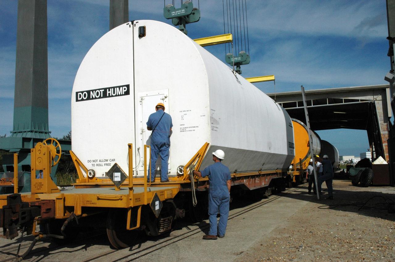 KENNEDY SPACE CENTER, FLA. --  A worker at the railroad yard at NASA's Kennedy Space Center secures the transportation cover over the solid rocket booster segment that is being transported to Utah.   After a mission, the spent boosters are recovered, cleaned, disassembled, refurbished and reused after each launch. After hydrolasing the interior of each segment, they are placed on flatbed trucks.  The individual booster segments are transferred to a railhead located at the railroad yard at NASA's Kennedy Space Center. The long train of segments is part of the twin solid rocket boosters used to launch space shuttle Discovery in October.  The NASA Railroad locomotive backs up the rail cars and the segment is lowered onto the car. The covered segments are moved to Titusville for interchange with Florida East Coast Railway to begin the trip back to Utah.  Photo credit: NASA/Amanda Diller