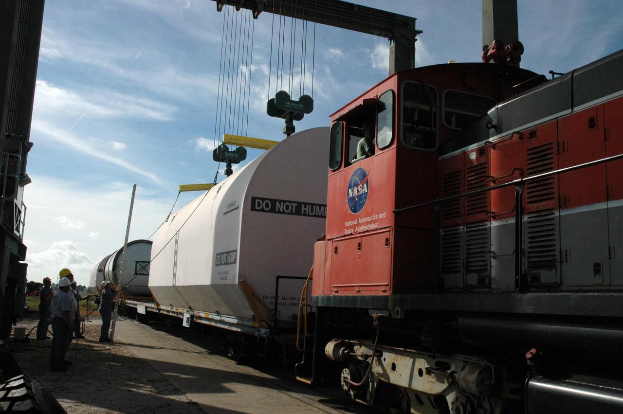 KENNEDY SPACE CENTER, FLA. --  At the railroad yard at NASA's Kennedy Space Center, workers release the crane from the transportation cover over the solid rocket booster segment.   After a mission, the spent boosters are recovered, cleaned, disassembled, refurbished and reused after each launch. After hydrolasing the interior of each segment, they are placed on flatbed trucks.  The individual booster segments are transferred to a railhead located at the railroad yard at NASA's Kennedy Space Center. The long train of segments is part of the twin solid rocket boosters used to launch space shuttle Discovery in October.  The NASA Railroad locomotive backs up the rail cars and the segment is lowered onto the car. The covered segments are moved to Titusville for interchange with Florida East Coast Railway to begin the trip back to Utah.  Photo credit: NASA/Amanda Diller