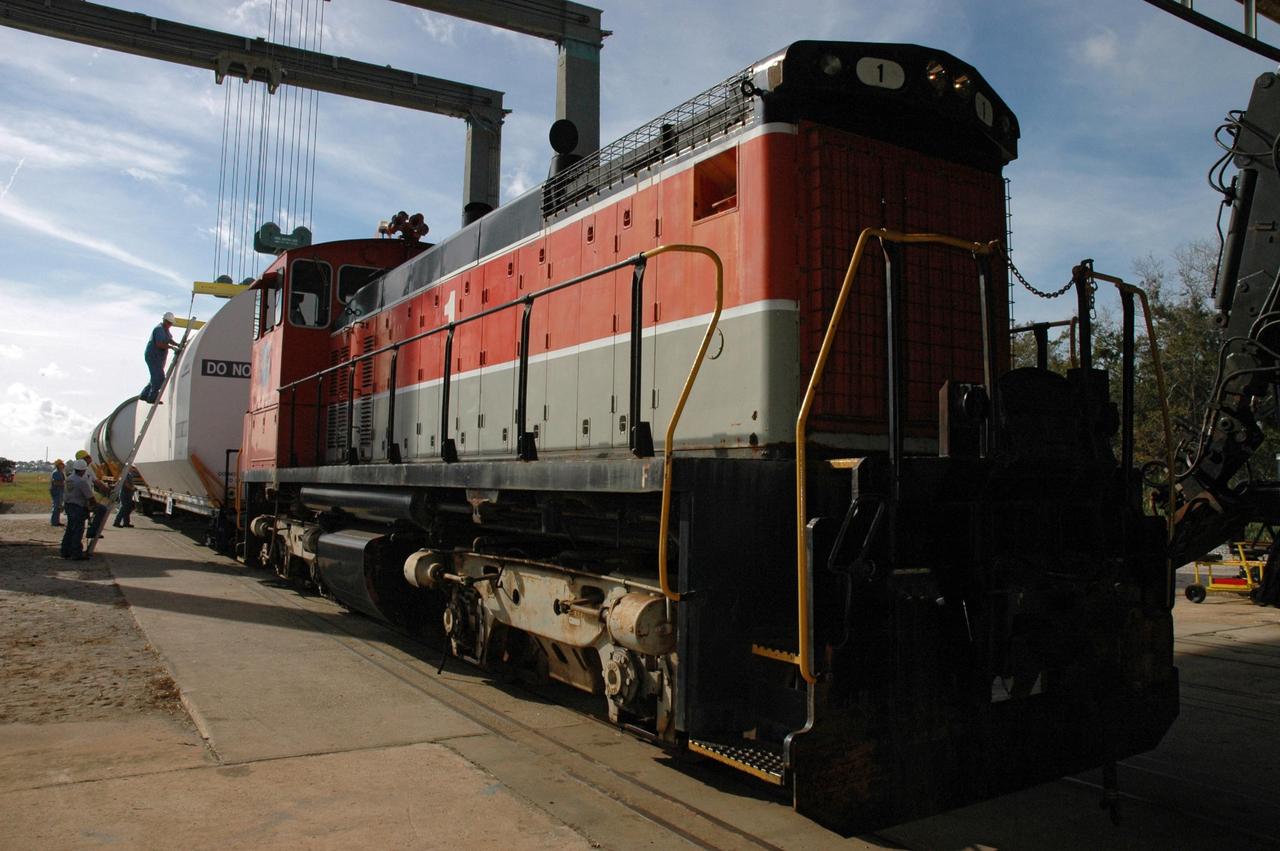 KENNEDY SPACE CENTER, FLA. --  At the railroad yard at NASA's Kennedy Space Center, workers release the crane from the transportation cover over the solid rocket booster segment.  After a mission, the spent boosters are recovered, cleaned, disassembled, refurbished and reused after each launch. After hydrolasing the interior of each segment, they are placed on flatbed trucks.  The individual booster segments are transferred to a railhead located at the railroad yard at NASA's Kennedy Space Center. The long train of segments is part of the twin solid rocket boosters used to launch space shuttle Discovery in October.  The NASA Railroad locomotive backs up the rail cars and the segment is lowered onto the car. The covered segments are moved to Titusville for interchange with Florida East Coast Railway to begin the trip back to Utah.  Photo credit: NASA/Amanda Diller