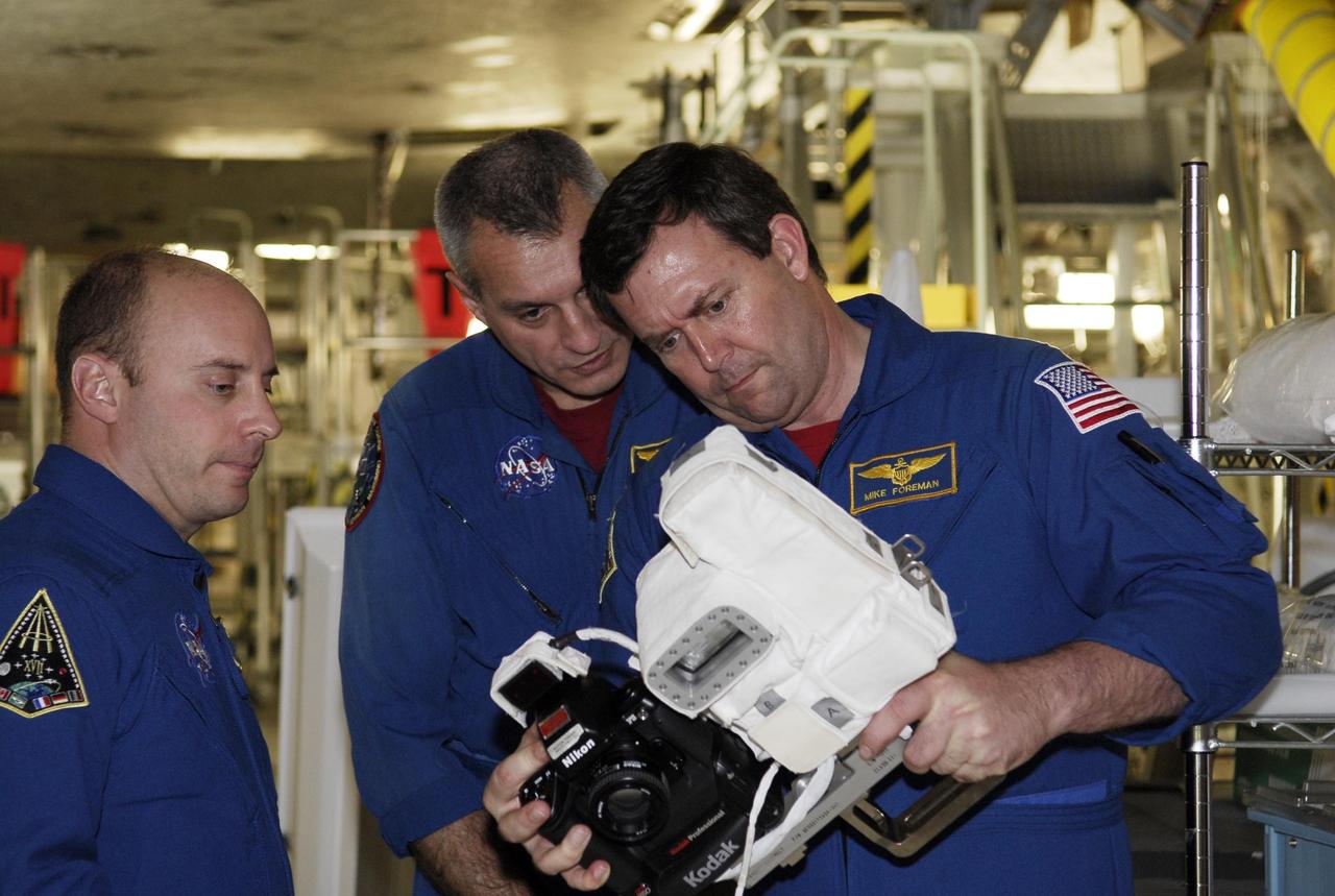 KENNEDY SPACE CENTER, FLA. -- In the Orbiter Processing Facility, STS-123 crew members examine one of the cameras that will be used on the mission. From left are Mission Specialists Garrett Reisman, Richard Linnehan and Michael Foreman. Reisman will join the Expedition 16 crew on the International Space Station, replacing flight engineer Leopold Eyharts. These and other crew members are at NASA's Kennedy Space Center for a crew equipment interface test, a process of familiarization with payloads, hardware and the space shuttle. The STS-123 mission is targeted for launch on space shuttle Endeavour on Feb. 14. It will be the 25th assembly flight of the station. Photo credit: NASA/Kim Shiflett