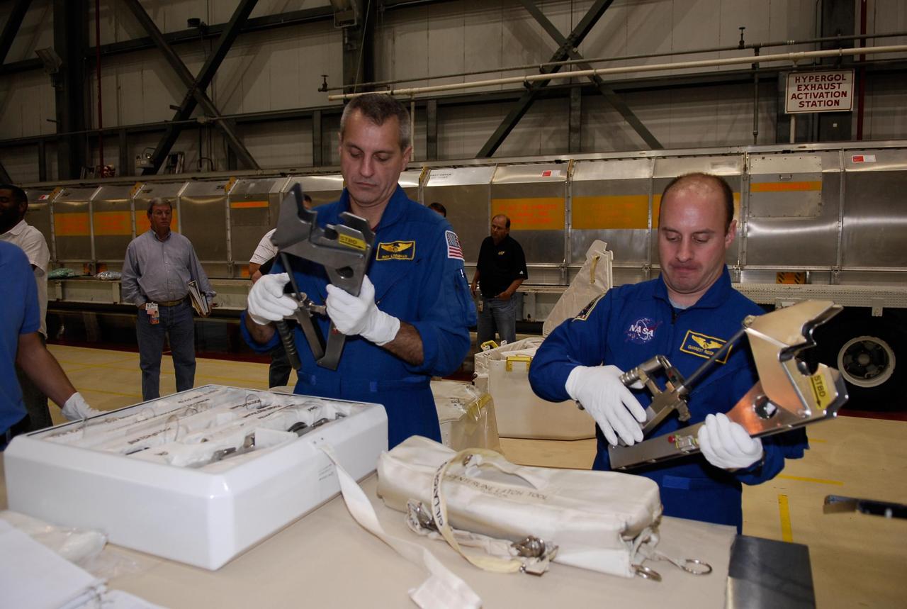 KENNEDY SPACE CENTER, FLA. -- In the Orbiter Processing Facility, STS-123 Mission Specialists Richard Linnehan (left) and Garrett Reisman practice with tools that will be used on the mission. They and other crew members are at NASA's Kennedy Space Center for a crew equipment interface test, a process of familiarization with payloads, hardware and the space shuttle. Reisman will join the Expedition 16 crew on the International Space Station, replacing flight engineer Leopold Eyharts. The STS-123 mission is targeted for launch on space shuttle Endeavour on Feb. 14. It will be the 25th assembly flight of the station. Photo credit: NASA/Kim Shiflett