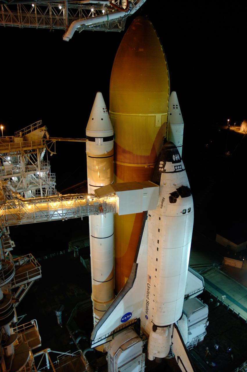 KENNEDY SPACE CENTER, FLA. -- Lights on Launch Pad 39A at NASA's Kennedy Space Center reveal space shuttle Atlantis following the rollback of the rotating service structure, or RSS. Rollback was complete at 9:49 p.m. EST. The orbiter access arm, at left, extends from the structure to a position next to Atlantis' crew compartment. The White Room at the end of the arm provides the crew with an entryway into the orbiter. The RSS also provides protected access to the orbiter for changeout and servicing of payloads at the pad. Rollback of the pad's RSS is one of the milestones in preparation for the launch of mission STS-122. Launch was originally set for Dec. 6 but was rescheduled to 3:21 p.m. Dec. 9. The delay was caused by problems with the external tank's engine cutoff sensor system that arose during tanking on Dec. 6. Atlantis will carry the Columbus Laboratory, the European Space Agency's largest contribution to the construction of the International Space Station. It will support scientific and technological research in a microgravity environment. Permanently attached to the Harmony node of the space station, the laboratory will carry out experiments in materials science, fluid physics and biosciences, as well as perform a number of technological applications. Photo credit: NASA/Amanda Diller
