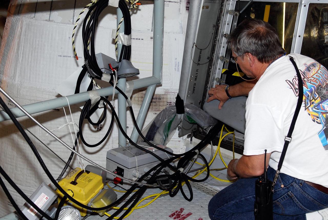 KENNEDY SPACE CENTER, FLA.  --  On Launch Pad 39A, a technician checks test wiring spliced into an electrical harness in space shuttle Atlantis' aft main engine compartment connected with the engine cut-off, or ECO, system. The test wiring leads to the interior of the mobile launcher platform where the Time Domain Reflectometry, or TDR, test equipment will be located to test the sensor system.  The shuttle's planned launches on Dec. 6 and Dec. 9 were postponed because of false readings from the part of the ECO system that monitors the liquid hydrogen section of the tank. The liftoff date from NASA's Kennedy Space Center, Florida, is now targeted for Jan. 10, depending on the resolution of the problem in the fuel sensor system.  Photo credit: NASA/Kim Shiflett
