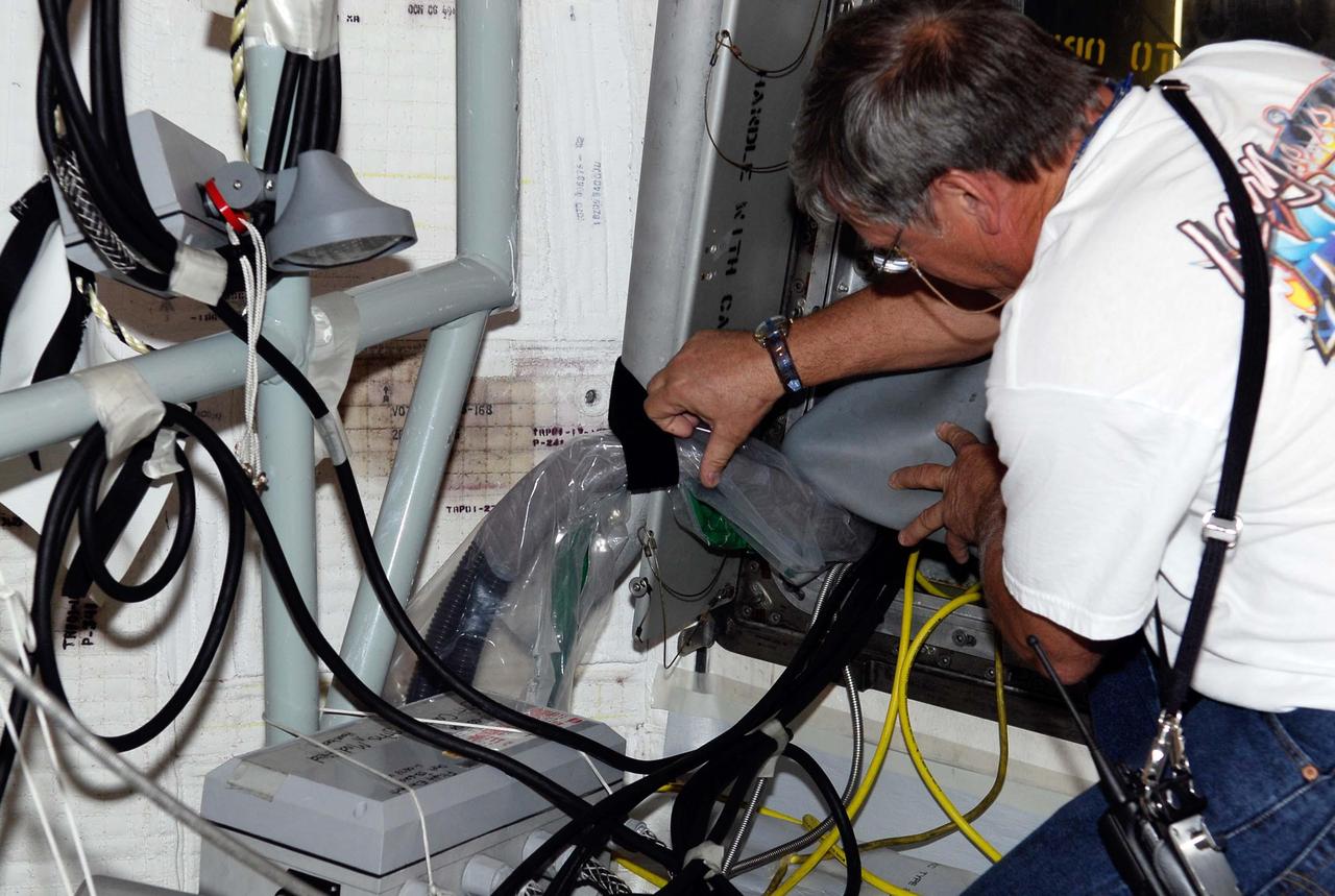 KENNEDY SPACE CENTER, FLA.  --  On Launch Pad 39A, a technician checks test wiring spliced into an electrical harness in space shuttle Atlantis' aft main engine compartment connected with the engine cut-off, or ECO, system. The test wiring leads to the interior of the mobile launcher platform where the Time Domain Reflectometry, or TDR, test equipment will be located to test the sensor system.   The shuttle's planned launches on Dec. 6 and Dec. 9 were postponed because of false readings from the part of the ECO system that monitors the liquid hydrogen section of the tank. The liftoff date from NASA's Kennedy Space Center, Florida, is now targeted for Jan. 10, depending on the resolution of the problem in the fuel sensor system.  Photo credit: NASA/Kim Shiflett
