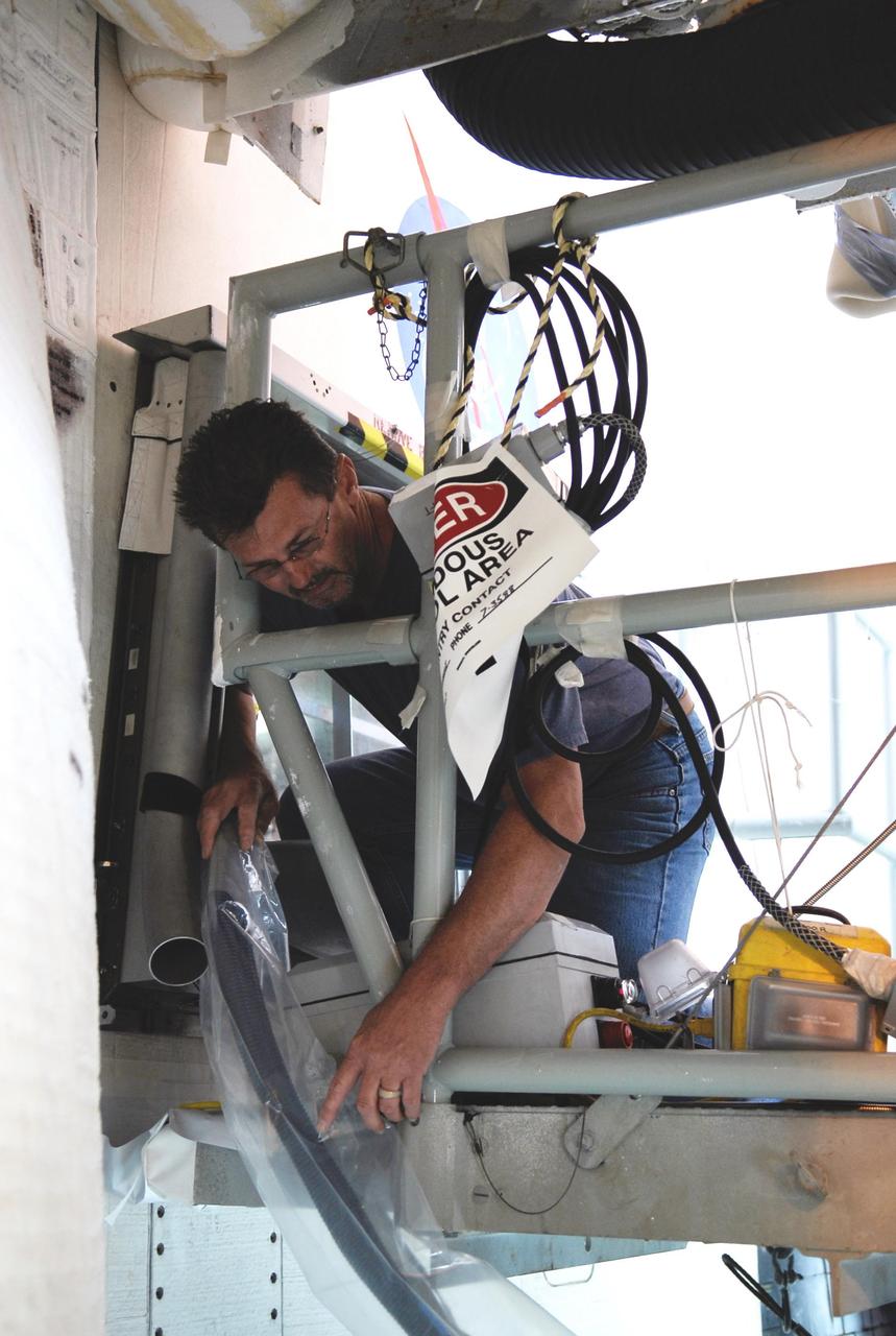 KENNEDY SPACE CENTER, FLA.  --  On Launch Pad 39A, a technician prepares a cable from an electrical harness in space shuttle Atlantis' aft main engine compartment connected with the engine cut-off, or ECO, system leading into the tail mast. The test wiring leads from the tail mast to the interior of the mobile launcher platform where the Time Domain Reflectometry, or TDR, test equipment will be located to test the sensor system.   The shuttle's planned launches on Dec. 6 and Dec. 9 were postponed because of false readings from the part of the ECO system that monitors the liquid hydrogen section of the tank. The liftoff date from NASA's Kennedy Space Center, Florida, is now targeted for Jan. 10, depending on the resolution of the problem in the fuel sensor system.  Photo credit: NASA/Kim Shiflett