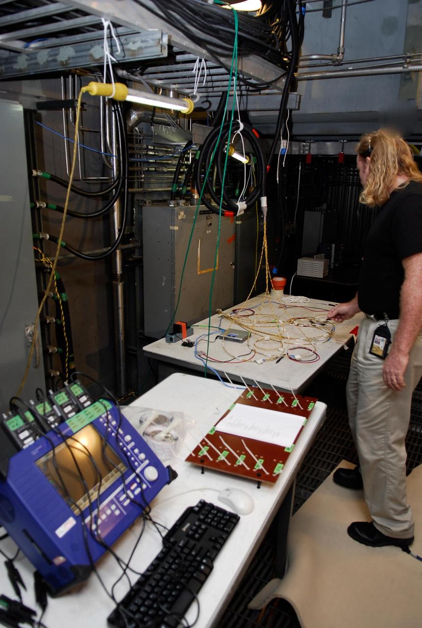KENNEDY SPACE CENTER, FLA.  --  On Launch Pad 39A, a technician checks cables and wires that will be used in the Time Domain Reflectometry, or TDR, test on engine cut-off sensors, or ECO, in space shuttle Atlantis' external tank. The test equipment -- blue monitor at left--  will be used to validate the circuit on the test wiring before hooking it up to the test box.  The shuttle's planned launches on Dec. 6 and Dec. 9 were postponed because of false readings from the part of the ECO system that monitors the liquid hydrogen section of the tank. The liftoff date from NASA's Kennedy Space Center, Florida, is now targeted for Jan. 10, depending on the resolution of the problem in the fuel sensor system.  Photo credit: NASA/Kim Shiflett