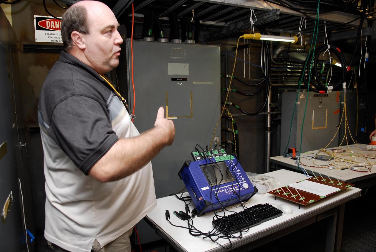 KENNEDY SPACE CENTER, FLA.  --  On Launch Pad 39A, a technician explains how test equipment -- the blue monitor -- will be used to validate the circuit on test wiring from the electrical harness in space shuttle Atlantis' aft main engine compartment connected with the engine cut-off system.  The test wiring leads from the tail mast on the mobile launcher platform to the interior where the Time Domain Reflectometry, or TDR, test equipment will be located to test the sensor system.  Photo credit: NASA/Kim Shiflett