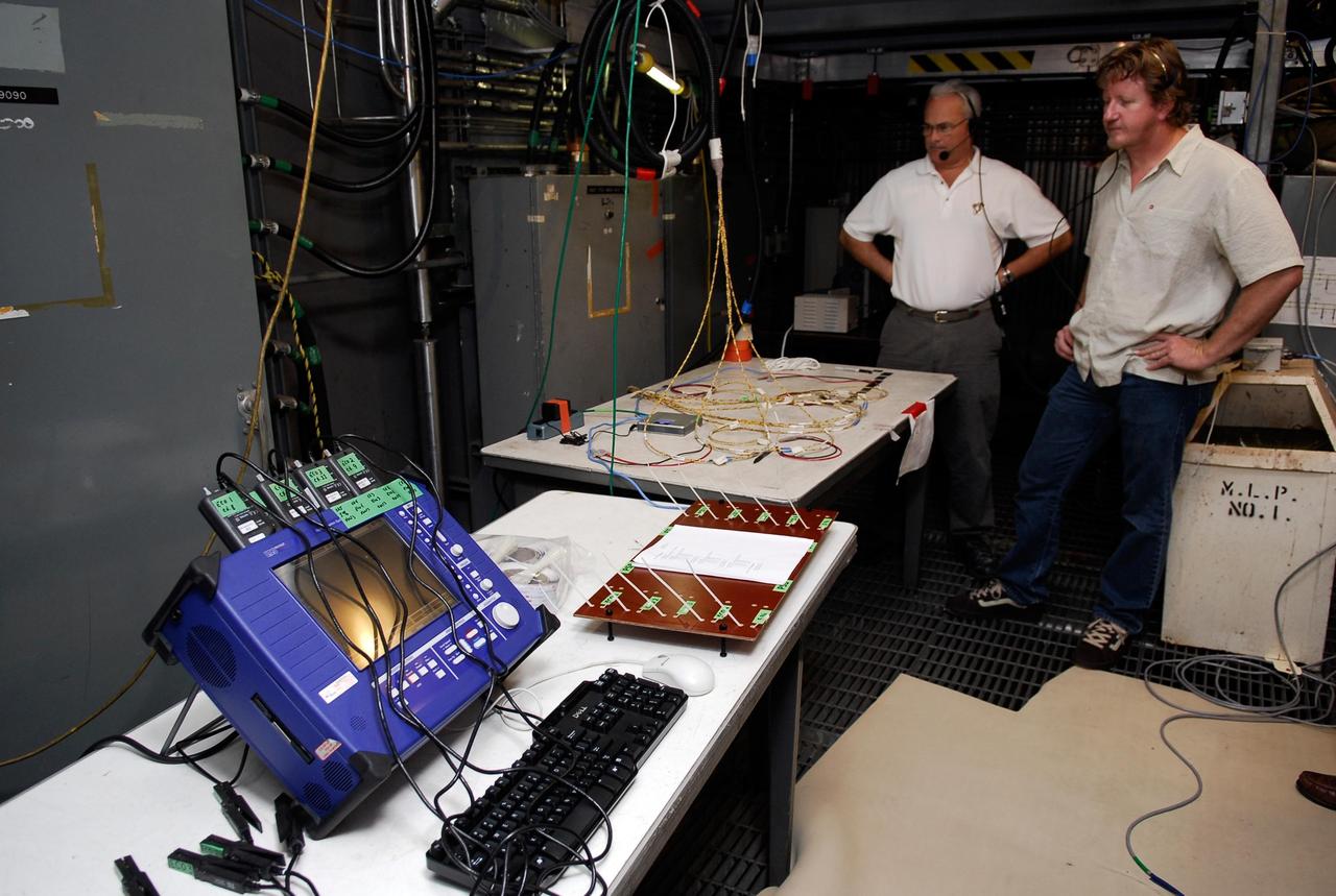 KENNEDY SPACE CENTER, FLA.  --  On Launch Pad 39A,  technicians overlook wires and monitoring equipment that will be used to validate the circuit on the test wiring from the electrical harness in space shuttle Atlantis' aft main engine compartment connected with the engine cut-off system. The test wiring leads from the tail mast on the mobile launcher platform to the interior where the Time Domain Reflectometry, or TDR, test equipment will be located to test the sensor system.  Photo credit: NASA/Kim Shiflett