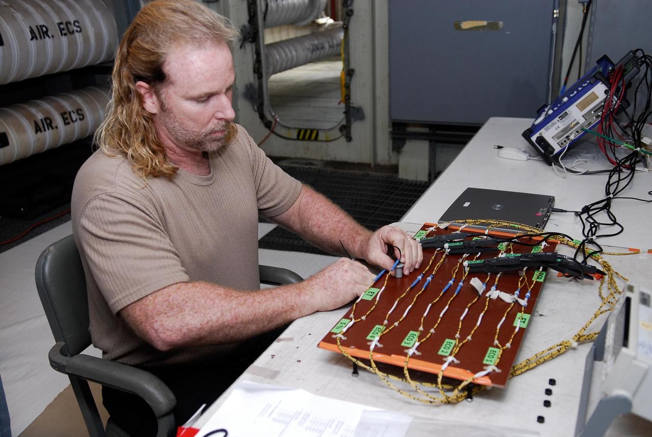 KENNEDY SPACE CENTER, FLA.  --   On Launch Pad 39A at NASA's Kennedy Space Center, a technician sets up wiring for the tanking test on space shuttle Atlantis' external tank set for Dec. 18.  The test wiring has been spliced into an electrical harness in the aft main engine compartment connected with the engine cut-off, or ECO, sensor system. The attached wiring leads to the interior of the mobile launcher platform where the time domain reflectometry, or TDR,  test equipment is located.  Photo credit: NASA/Kim Shiflett