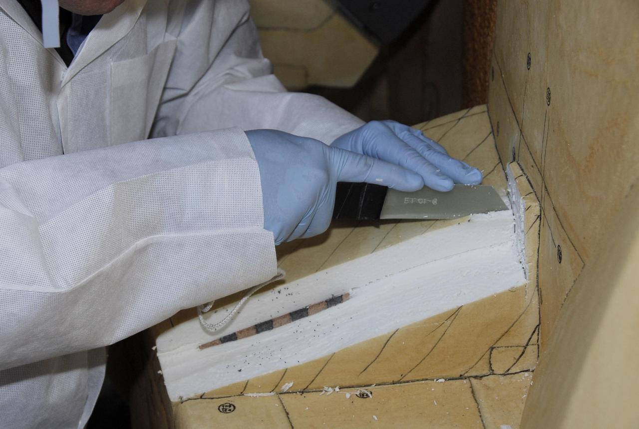 KENNEDY SPACE CENTER, FLA. -- At Launch Pad 39A, the foam insulation surrounding the covers over the feed-through connector box on the external tank for space shuttle Atlantis' STS-122 mission is carefully cut away by a United Space Alliance technician.  The covers will be removed for access to the feed-through connectors.  Following the failure of some of the tank's engine cutoff sensors, or ECO sensors, during propellant tanking for launch attempts on Dec. 6 and Dec. 9, a tanking test was conducted on Dec. 18 to aid in troubleshooting the cause. Technicians spliced test wiring into the ECO sensor electrical system and used time domain reflectometry equipment to help locate the electrical anomaly. Results of the tanking test pointed to an open circuit in the feed-through connector wiring, which is located at the base of the tank. The feed-through connector passes the wires from the inside of the tank to the outside.  During the holiday period, workers from Lockheed Martin will begin inspecting and testing the connector.  Shuttle program managers will meet on Dec. 27 to review the test and analysis, and decide on a forward plan.  Photo credit: NASA/Kim Shiflett