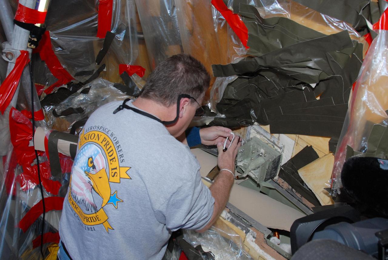 KENNEDY SPACE CENTER, FLA. -- At Launch Pad 39A, a team of external tank specialists from Lockheed Martin and the United Space Alliance undertakes the task of removing the hydrogen feed-through connector in support of space shuttle Atlantis' STS-122 mission.  Here, a technician cuts the external connector cable. Some of the tank's engine cutoff sensors, or ECO sensors, failed during propellant tanking for launch attempts on Dec. 6 and Dec. 9.  Results of a tanking test on Dec. 18 pointed to an open circuit in the feed-through connector wiring, which is located at the base of the tank. The feed-through connector passes the wires from the inside of the tank to the outside.  After the data from additional testing on the connector is analyzed, shuttle program managers will decide on a forward plan.  Launch of STS-122 is targeted for January 2008.  Photo credit: NASA/George Shelton