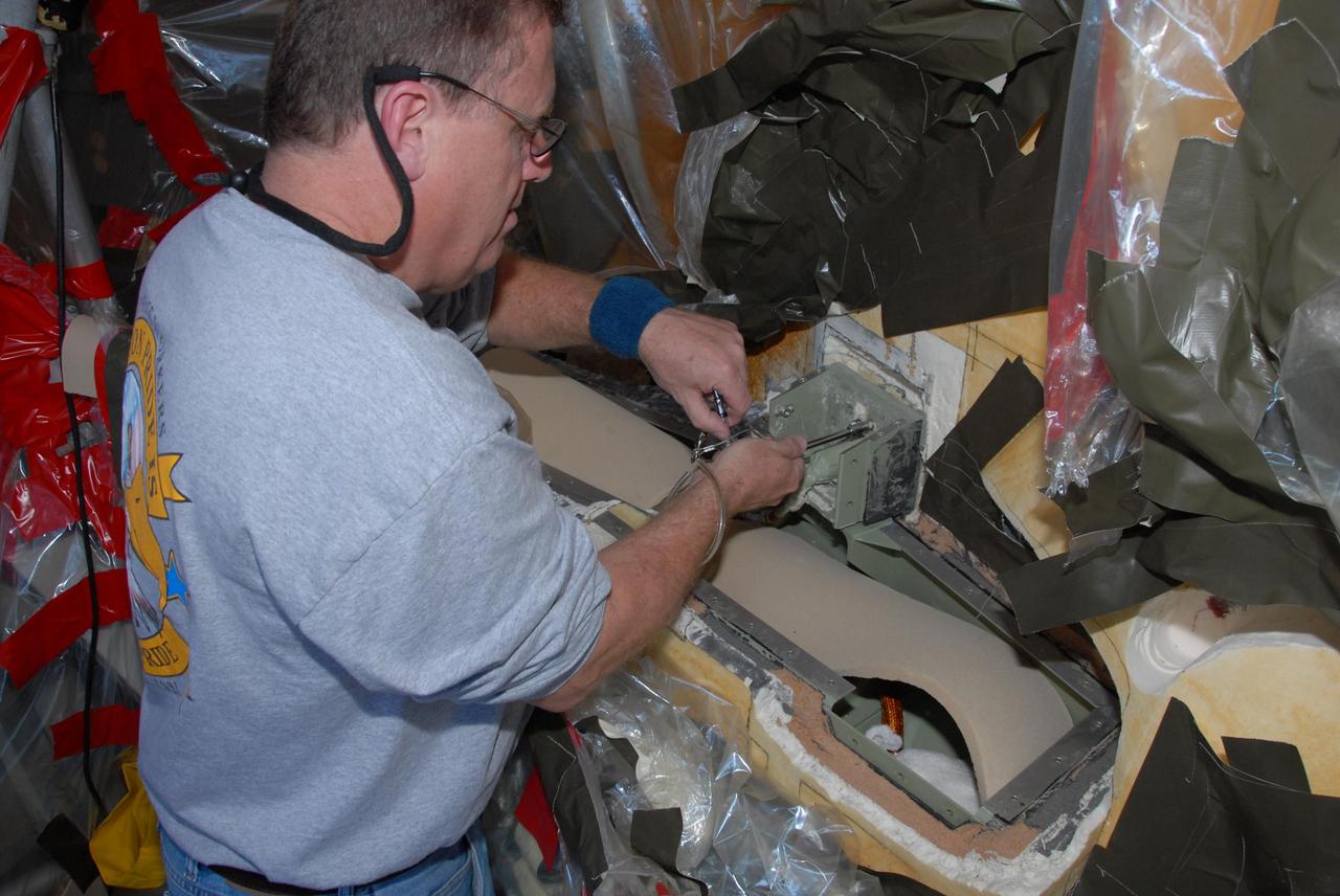 KENNEDY SPACE CENTER, FLA. -- At Launch Pad 39A, a team of external tank specialists from Lockheed Martin and the United Space Alliance undertakes the task of removing the hydrogen feed-through connector in support of space shuttle Atlantis' STS-122 mission.  Here, a technician removes a pair of support brackets.  Some of the tank's engine cutoff sensors, or ECO sensors, failed during propellant tanking for launch attempts on Dec. 6 and Dec. 9.  Results of a tanking test on Dec. 18 pointed to an open circuit in the feed-through connector wiring, which is located at the base of the tank. The feed-through connector passes the wires from the inside of the tank to the outside.  After the data from additional testing on the connector is analyzed, shuttle program managers will decide on a forward plan.  Launch of STS-122 is targeted for January 2008.  Photo credit: NASA/George Shelton