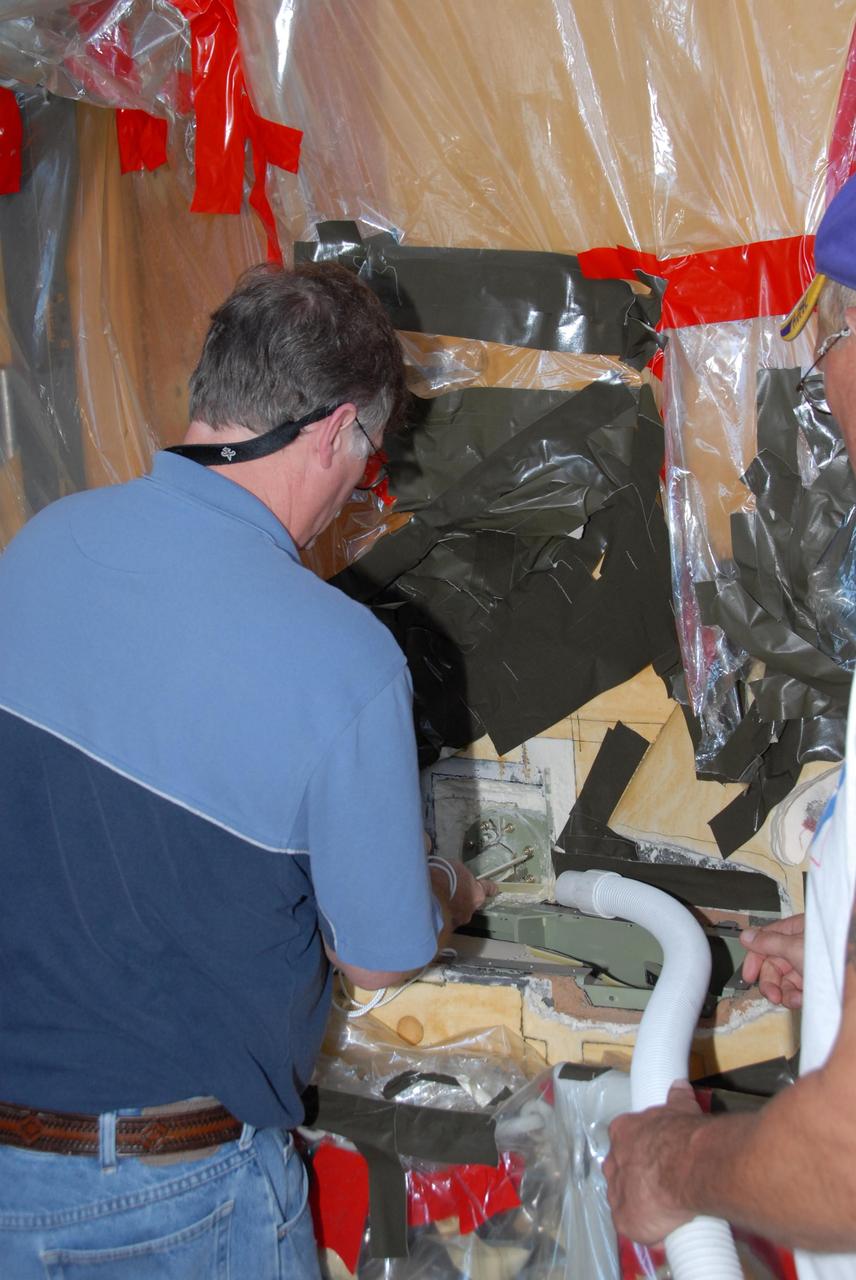 KENNEDY SPACE CENTER, FLA. -- At Launch Pad 39A, a team of external tank specialists from Lockheed Martin and the United Space Alliance undertakes the task of removing the hydrogen feed-through connector in support of space shuttle Atlantis' STS-122 mission.  Here, a technician gives the connector a cleaning, removing any residual foam insulation, and begins disconnecting the connector assembly.   Some of the tank's engine cutoff sensors, or ECO sensors, failed during propellant tanking for launch attempts on Dec. 6 and Dec. 9.  Results of a tanking test on Dec. 18 pointed to an open circuit in the feed-through connector wiring, which is located at the base of the tank. The feed-through connector passes the wires from the inside of the tank to the outside.  After the data from additional testing on the connector is analyzed, shuttle program managers will decide on a forward plan.  Launch of STS-122 is targeted for January 2008.  Photo credit: NASA/George Shelton