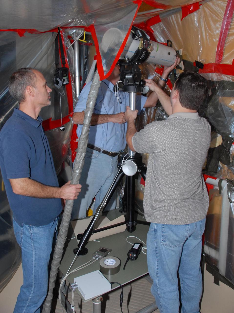 KENNEDY SPACE CENTER, FLA. -- At Launch Pad 39A, a team of external tank specialists from Lockheed Martin and the United Space Alliance undertakes the task of removing the hydrogen feed-through connector in support of space shuttle Atlantis' STS-122 mission.  Here, technicians set up equipment that will be used to take X-rays of the connector cable.   Some of the tank's engine cutoff sensors, or ECO sensors, failed during propellant tanking for launch attempts on Dec. 6 and Dec. 9.  Results of a tanking test on Dec. 18 pointed to an open circuit in the feed-through connector wiring, which is located at the base of the tank. The feed-through connector passes the wires from the inside of the tank to the outside.  After the data from additional testing on the connector is analyzed, shuttle program managers will decide on a forward plan.  Launch of STS-122 is targeted for January 2008.  Photo credit: NASA/George Shelton