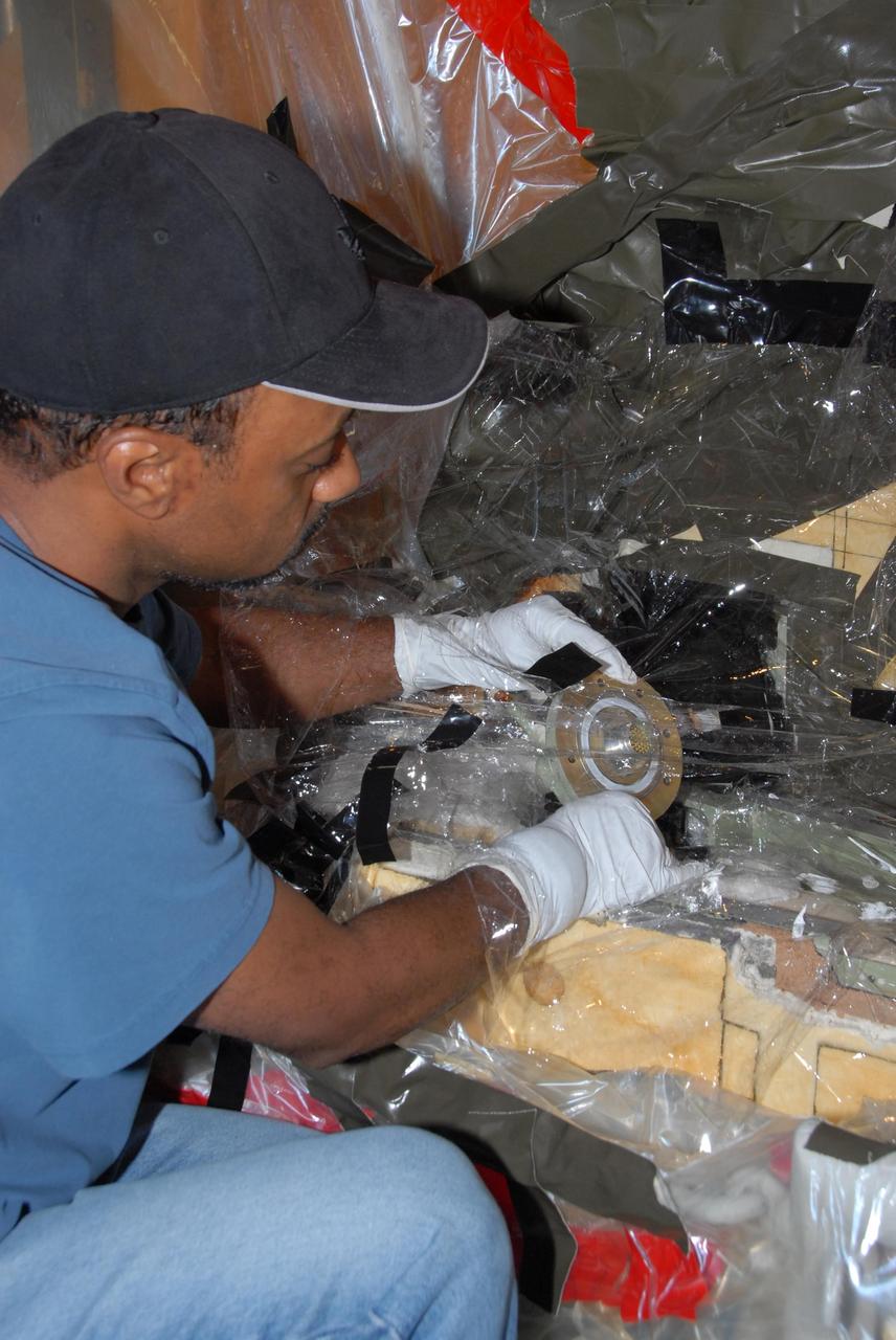 KENNEDY SPACE CENTER, FLA. -- At Launch Pad 39A, a team of external tank specialists from Lockheed Martin and the United Space Alliance undertakes the task of removing the hydrogen feed-through connector in support of space shuttle Atlantis' STS-122 mission.  Here, a technician demates the connector from the external tank.  Some of the tank's engine cutoff sensors, or ECO sensors, failed during propellant tanking for launch attempts on Dec. 6 and Dec. 9.  Results of a tanking test on Dec. 18 pointed to an open circuit in the feed-through connector wiring, which is located at the base of the tank. The feed-through connector passes the wires from the inside of the tank to the outside.  After the data from additional testing on the connector is analyzed, shuttle program managers will decide on a forward plan.  Launch of STS-122 is targeted for January 2008.  Photo credit: NASA/George Shelton
