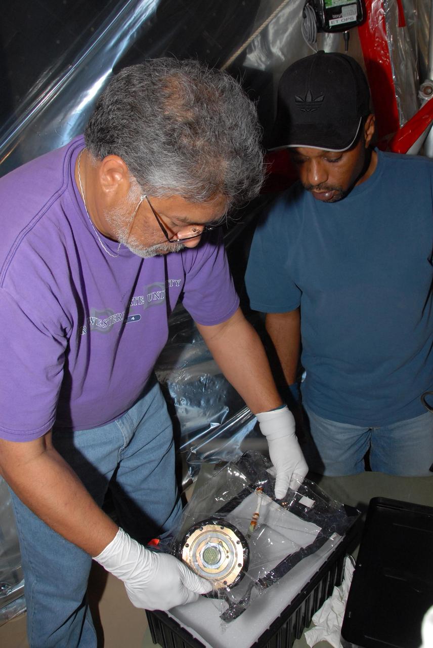 KENNEDY SPACE CENTER, FLA. -- At Launch Pad 39A, a team of external tank specialists from Lockheed Martin and the United Space Alliance undertakes the task of removing the hydrogen feed-through connector in support of space shuttle Atlantis' STS-122 mission.  Here, technicians place the wrapped connector in a shipping container for transport to NASA's Marshall Space Flight Center in Huntsville, Ala., for further cryogenic testing.   Some of the tank's engine cutoff sensors, or ECO sensors, failed during propellant tanking for launch attempts on Dec. 6 and Dec. 9.  Results of a tanking test on Dec. 18 pointed to an open circuit in the feed-through connector wiring, which is located at the base of the tank. The feed-through connector passes the wires from the inside of the tank to the outside.  After the data from additional testing on the connector is analyzed, shuttle program managers will decide on a forward plan.  Launch of STS-122 is targeted for January 2008.  Photo credit: NASA/George Shelton