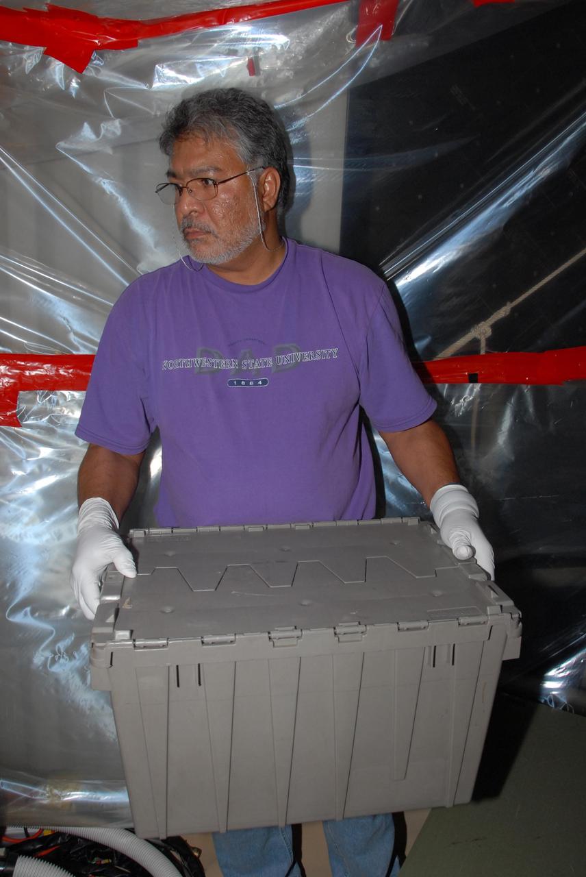 KENNEDY SPACE CENTER, FLA. -- At Launch Pad 39A, a team of external tank specialists from Lockheed Martin and the United Space Alliance undertakes the task of removing the hydrogen feed-through connector in support of space shuttle Atlantis' STS-122 mission.  Here, a technician carries the shipping container in which the wrapped connector is secured for transport to NASA's Marshall Space Flight Center in Huntsville, Ala., for further cryogenic testing.   Some of the tank's engine cutoff sensors, or ECO sensors, failed during propellant tanking for launch attempts on Dec. 6 and Dec. 9.  Results of a tanking test on Dec. 18 pointed to an open circuit in the feed-through connector wiring, which is located at the base of the tank. The feed-through connector passes the wires from the inside of the tank to the outside.  After the data from additional testing on the connector is analyzed, shuttle program managers will decide on a forward plan.  Launch of STS-122 is targeted for January 2008.  Photo credit: NASA/George Shelton