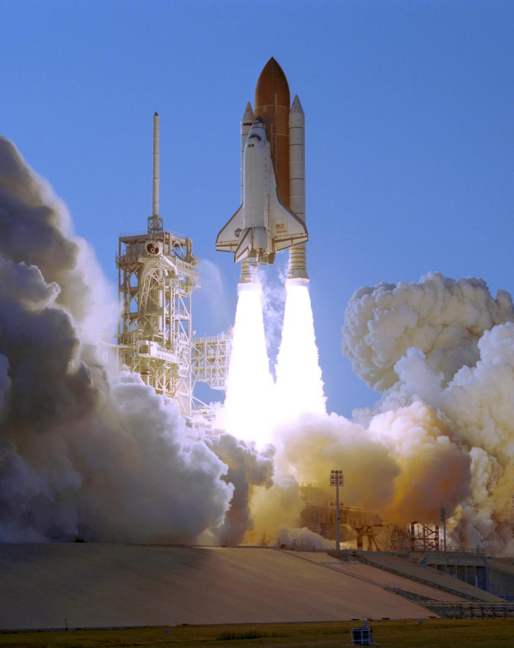 KENNEDY SPACE CENTER, FLA. --    Smoke and steam billow across Launch Pad 39A as Space Shuttle Atlantis, trailing columns of fire from the solid rocket boosters, hurtles into the sky on mission STS-117 to the International Space Station. At left is the fixed service structure with the 80-foot-tall lightning mast on top.  Liftoff was on-time at 7:38:04 p.m. EDT. The shuttle is delivering a new segment to the starboard side of the International Space Station's backbone, known as the truss. Three spacewalks are planned to install the S3/S4 truss segment, deploy a set of solar arrays and prepare them for operation. STS-117 is the 118th space shuttle flight, the 21st flight to the station, the 28th flight for Atlantis and the first of four flights planned for 2007.  Photo Credit: NASA/Tony Gray & Don Kight