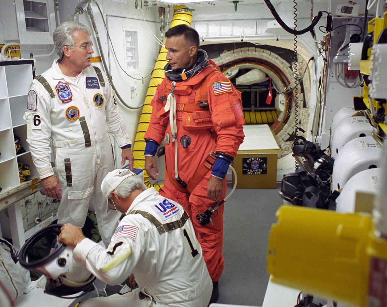 KENNEDY SPACE CENTER, FLA. --  STS-117 Pilot Lee Archambault is helped by the closeout crew in the White Room to secure his launch suit before climbing into Space Shuttle Atlantis.  The mission to the International Space Station is scheduled to launch at 7:38 p.m. EDT. Members of the closeout crew help the astronauts don a parachute pack, strap them into the space shuttle's crew module and take care of any other last-minute needs that arise. The White Room is at the end of the orbiter access arm that extends from the fixed service structure and provides entry into the orbiter. The shuttle is delivering a new segment to the starboard side of the space station's backbone, known as the truss. Three spacewalks are planned to install the S3/S4 truss segment, deploy a set of solar arrays and prepare them for operation. STS-117 is the 118th space shuttle flight, the 21st flight to the station, the 28th flight for Atlantis and the first of four flights planned for 2007.  Photo credit: NASA/Tony Gray & Don Kight